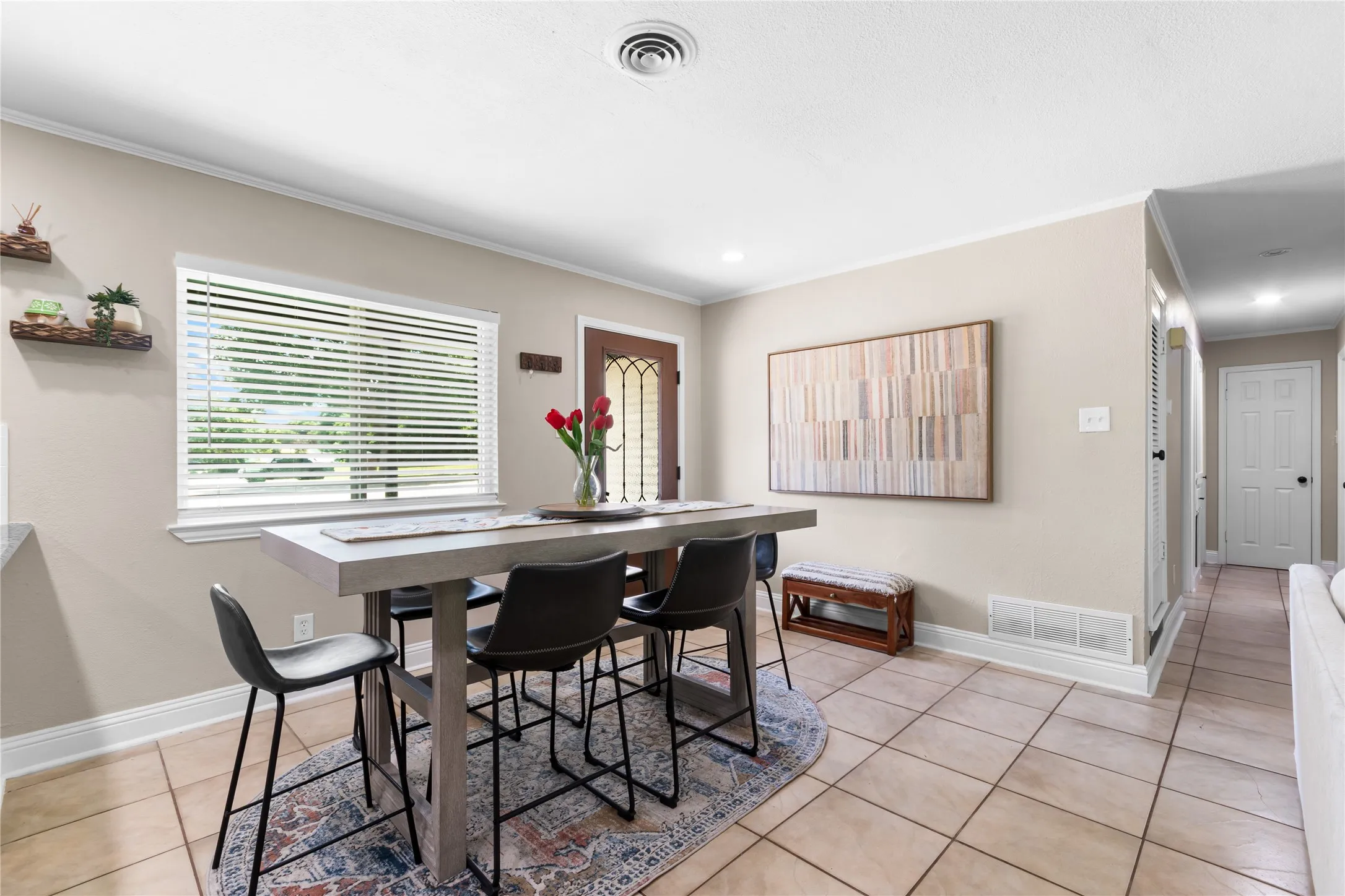 Spacious room featuring tile flooring, a large window, recessed lighting, and crown molding