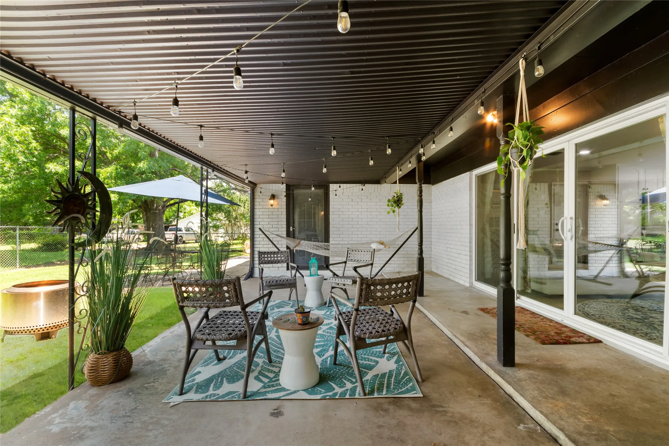Covered concrete patio featuring string lighting and a corrugated metal ceiling