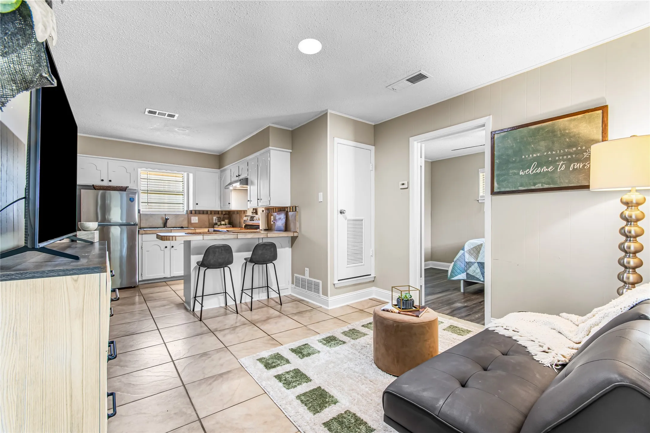Casita Open-concept living space featuring a kitchen with white cabinetry, stainless steel refrigerator, and a breakfast bar with seating