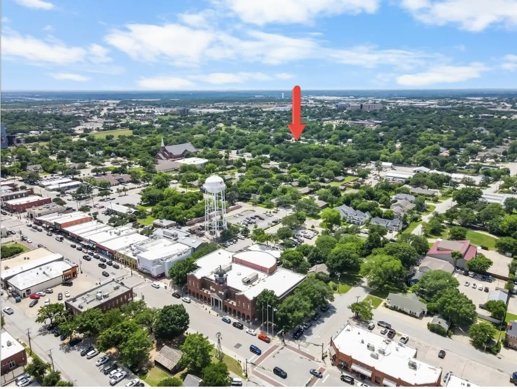 Expansive aerial perspective showcasing a town center, residential areas, and abundant green spaces under a clear sky