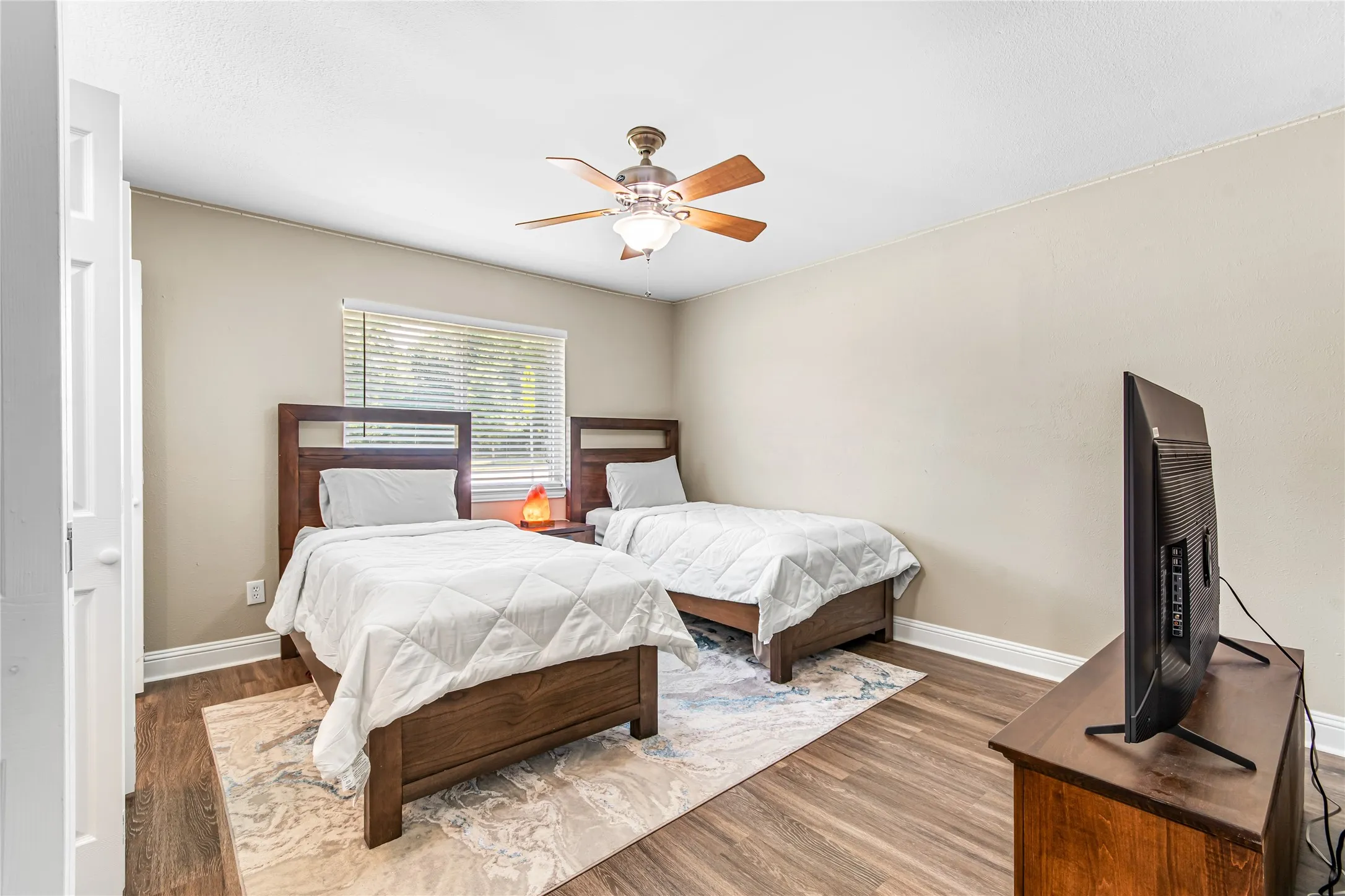 Bedroom featuring woodlike-finish flooring, a ceiling fan with light fixture, and a window with blinds