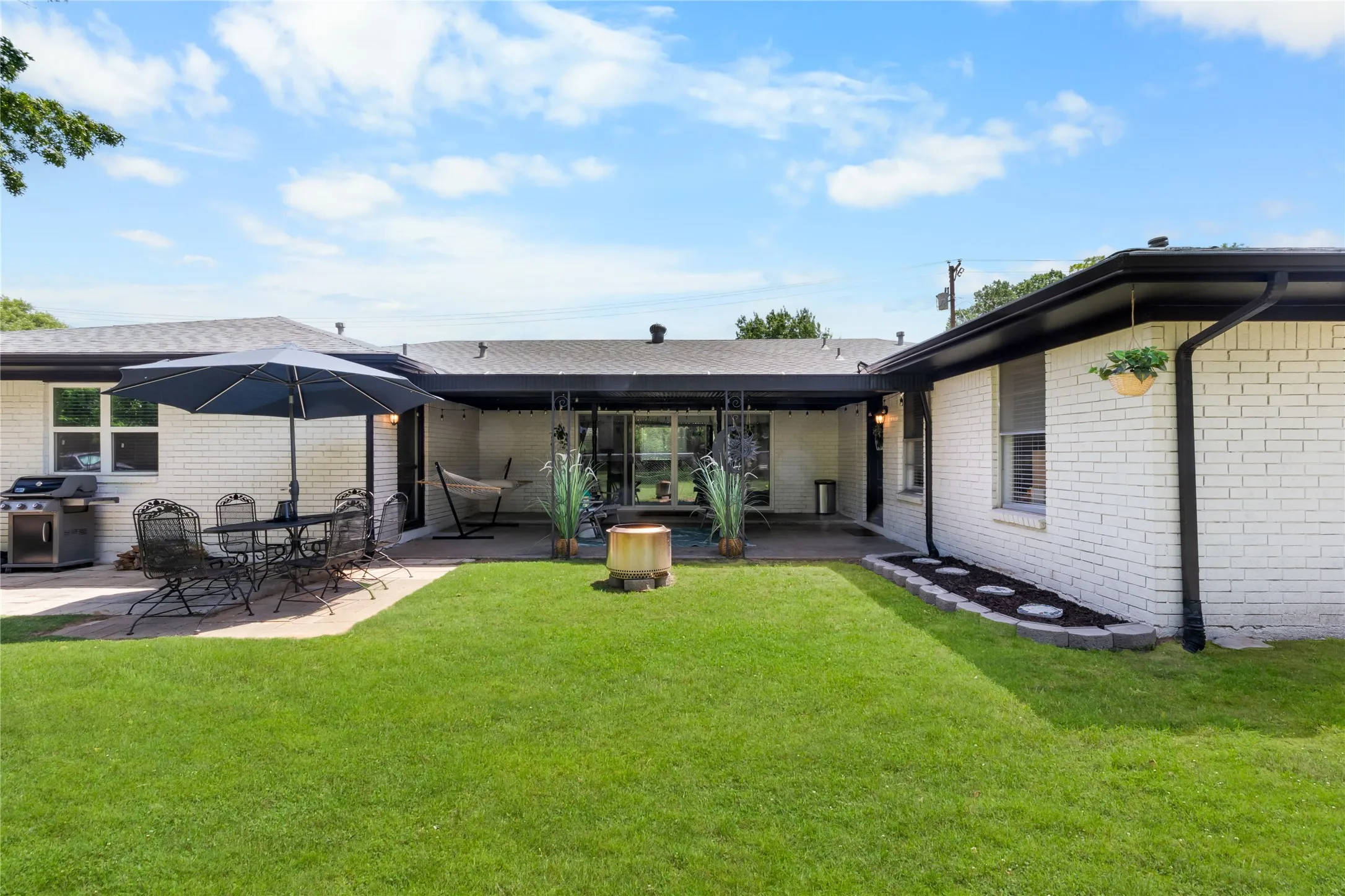 Spacious backyard featuring a manicured lawn, a large paver patio, and a covered patio area