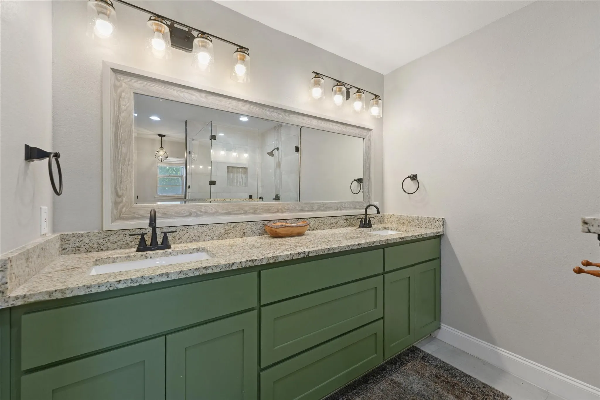 Dual granite vanity with custom cabinetry, updated lighting, and generous storage in the beautifully remodeled primary bathroom.