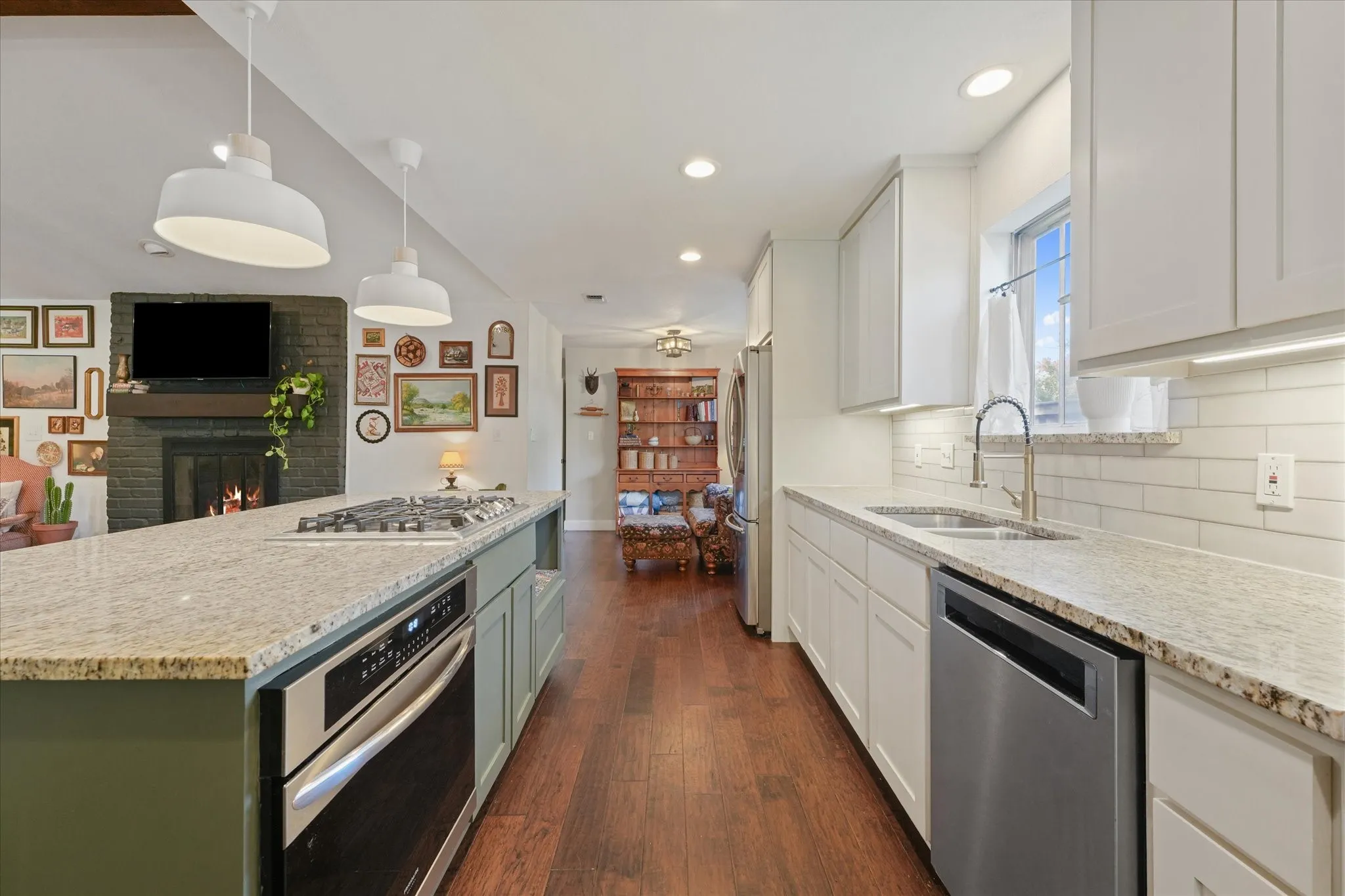 Open-concept kitchen with oversized island, gas cooktop, granite countertops, stainless steel appliances, and seamless flow into the living and dining areas.