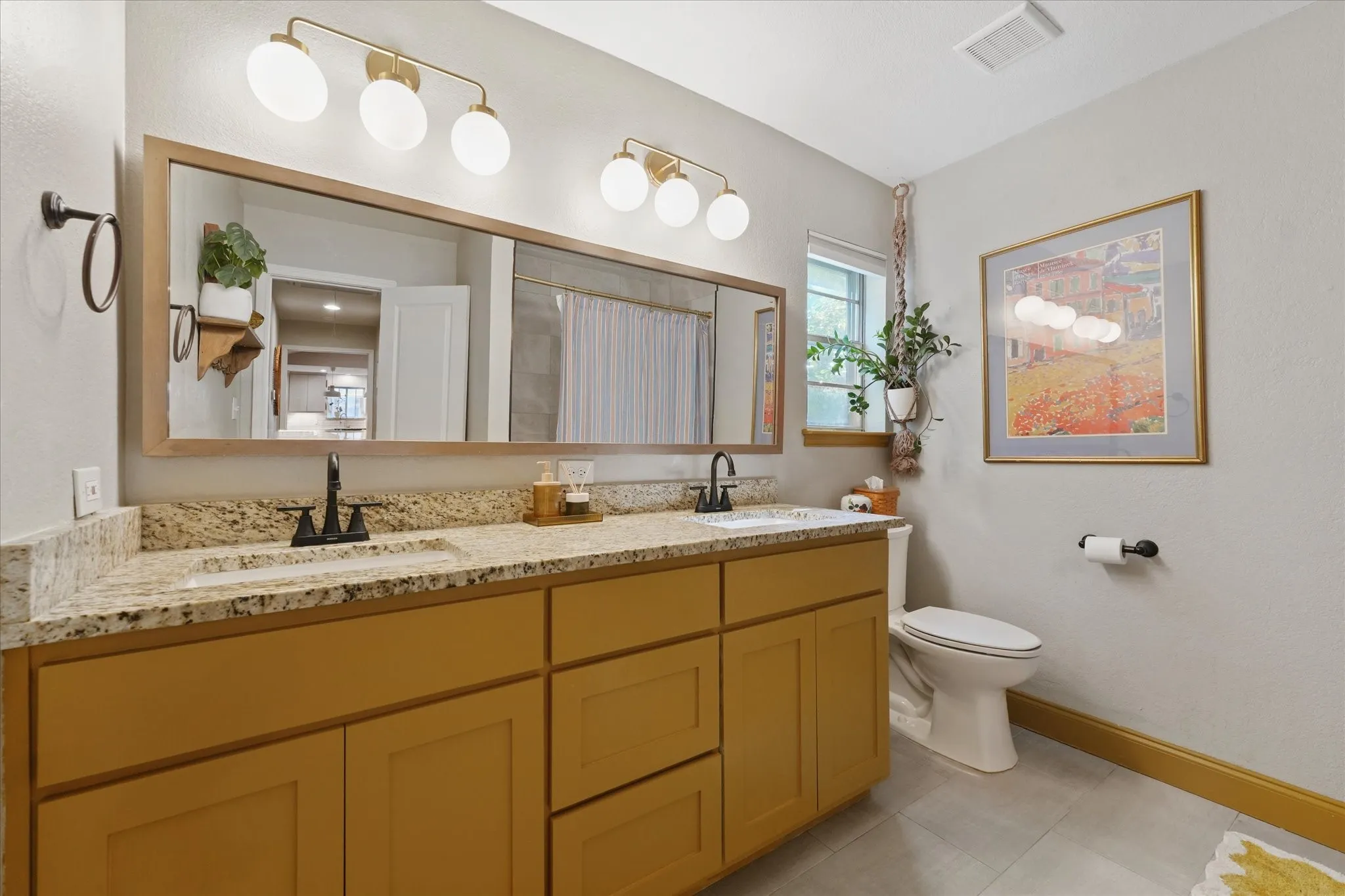Updated hall bathroom with dual granite vanities, modern lighting, updated fixtures, and abundant counter space serving the secondary bedrooms.