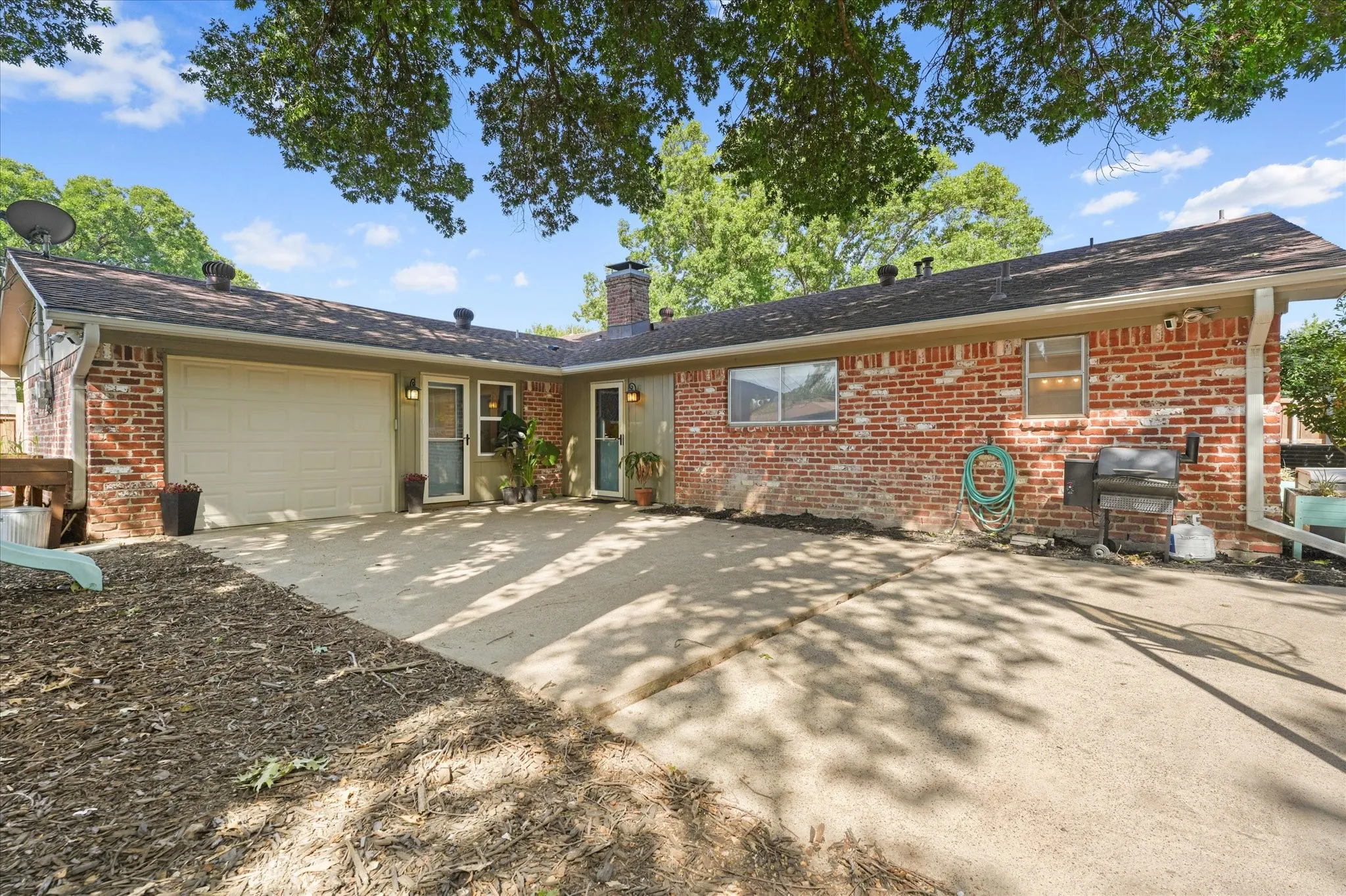 Large concrete patio overlooking the backyard with direct access to the home, ideal for outdoor dining, grilling, relaxing, or hosting gatherings beneath mature shade trees.