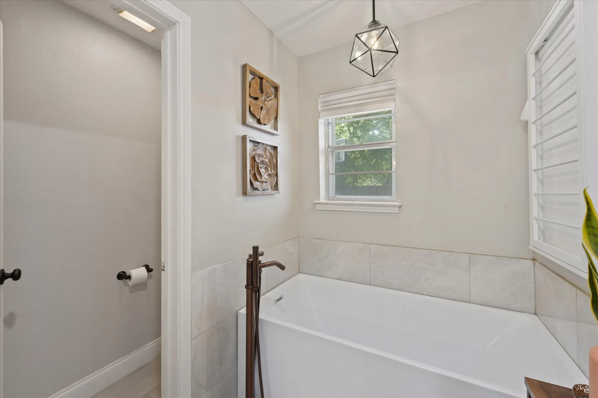 Relaxing freestanding soaking tub with natural light, modern fixtures, and a peaceful retreat within the renovated primary bathroom.