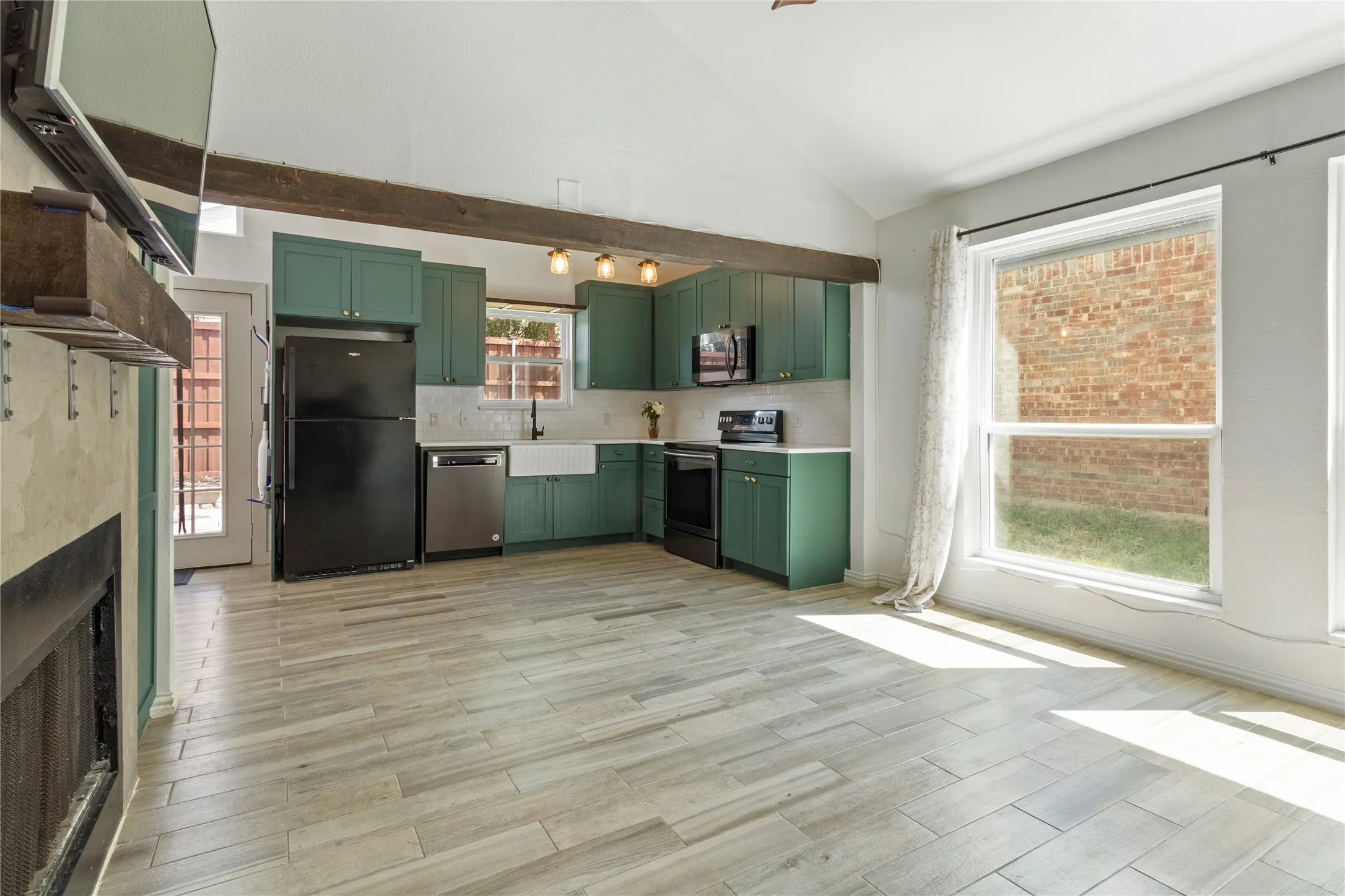 Kitchen with painted cabinetry, wood-finish flooring, vaulted ceiling, and exposed beam