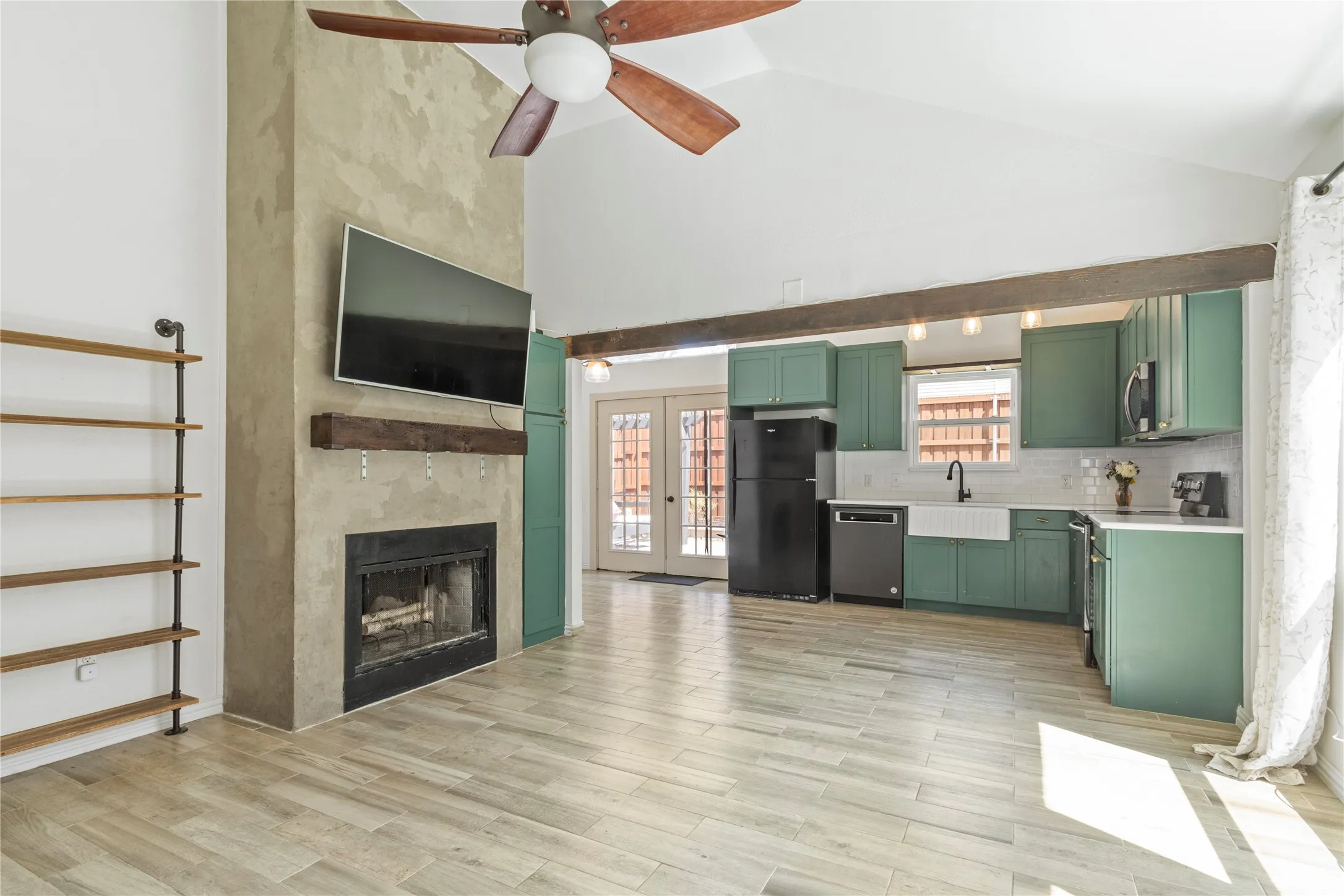 Vaulted ceiling with wood-finish fan, wood-look flooring, and a fireplace with a wood-beam mantel