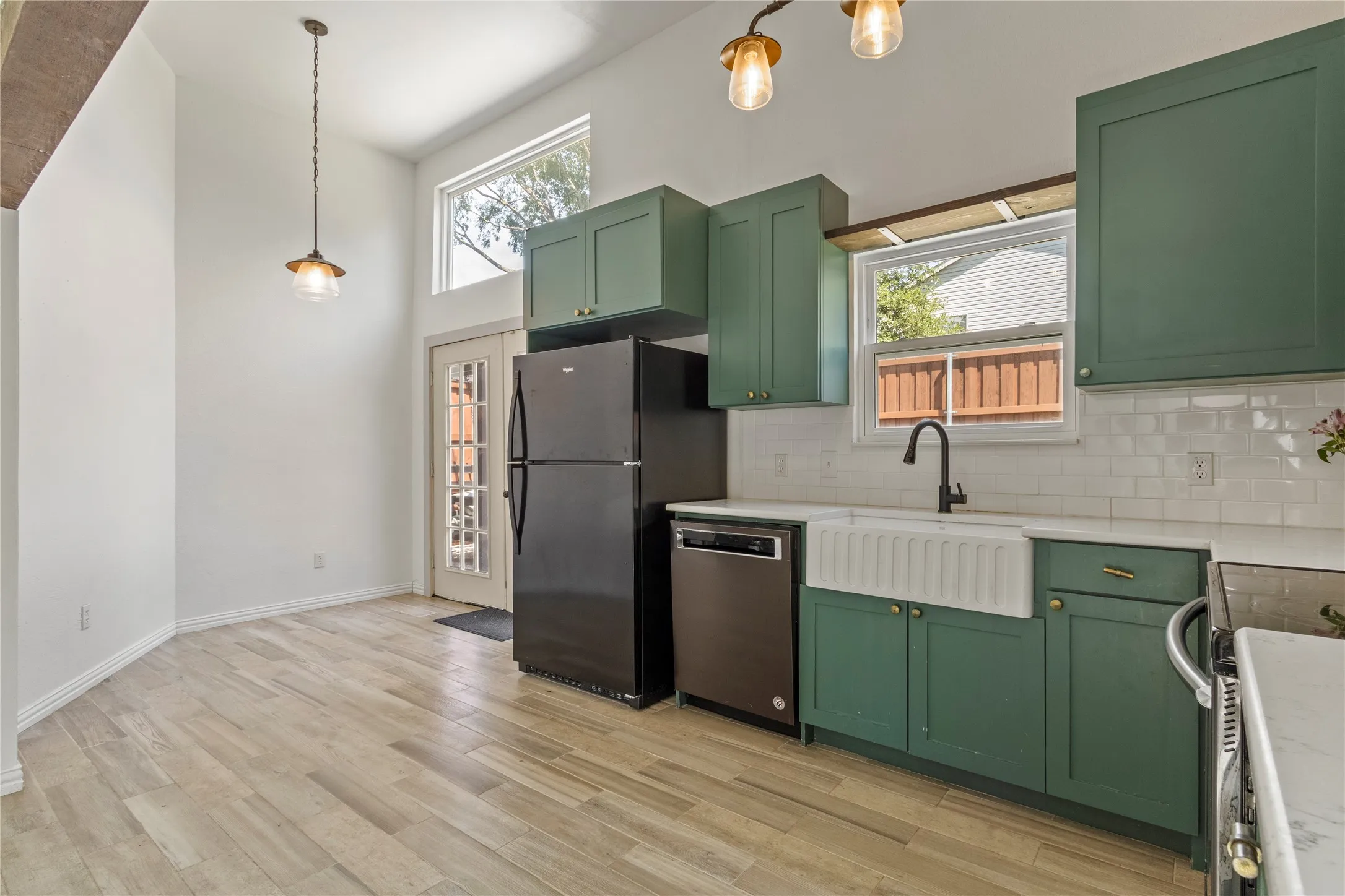 Kitchen featuring green cabinetry, a white farmhouse sink, white subway tile backsplash, and light wood-finish flooring
