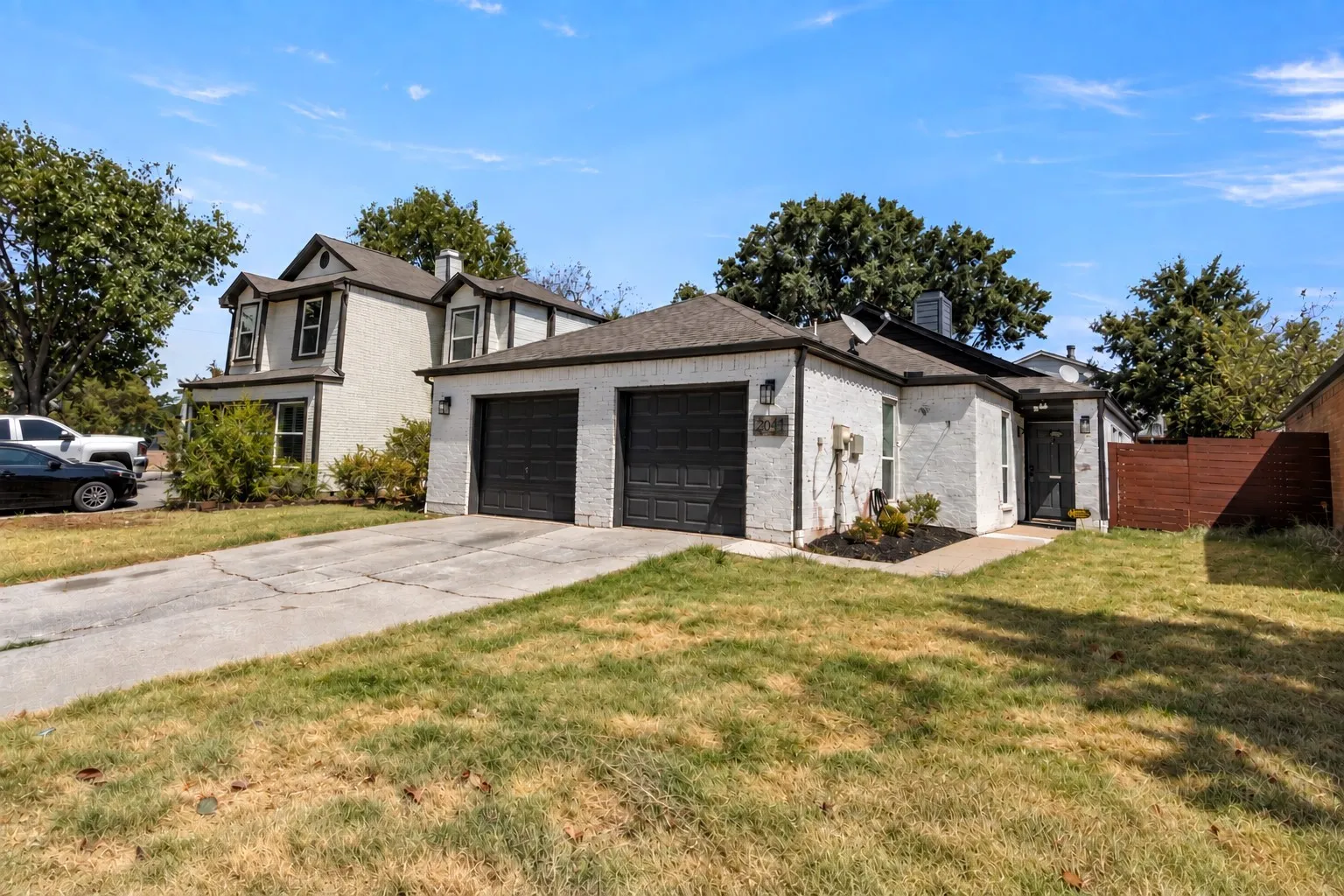 White stucco exterior, dark trim windows, and a dark wood-finish privacy fence