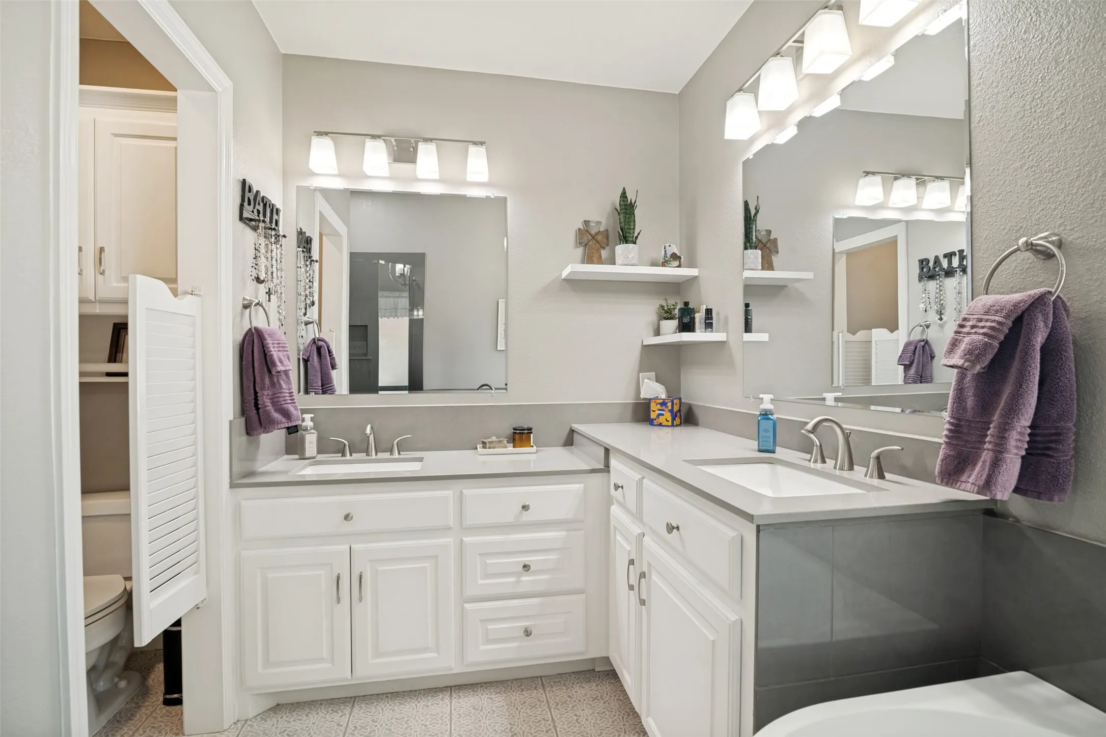 Updated primary bathroom has new floors, sinks and countertops.