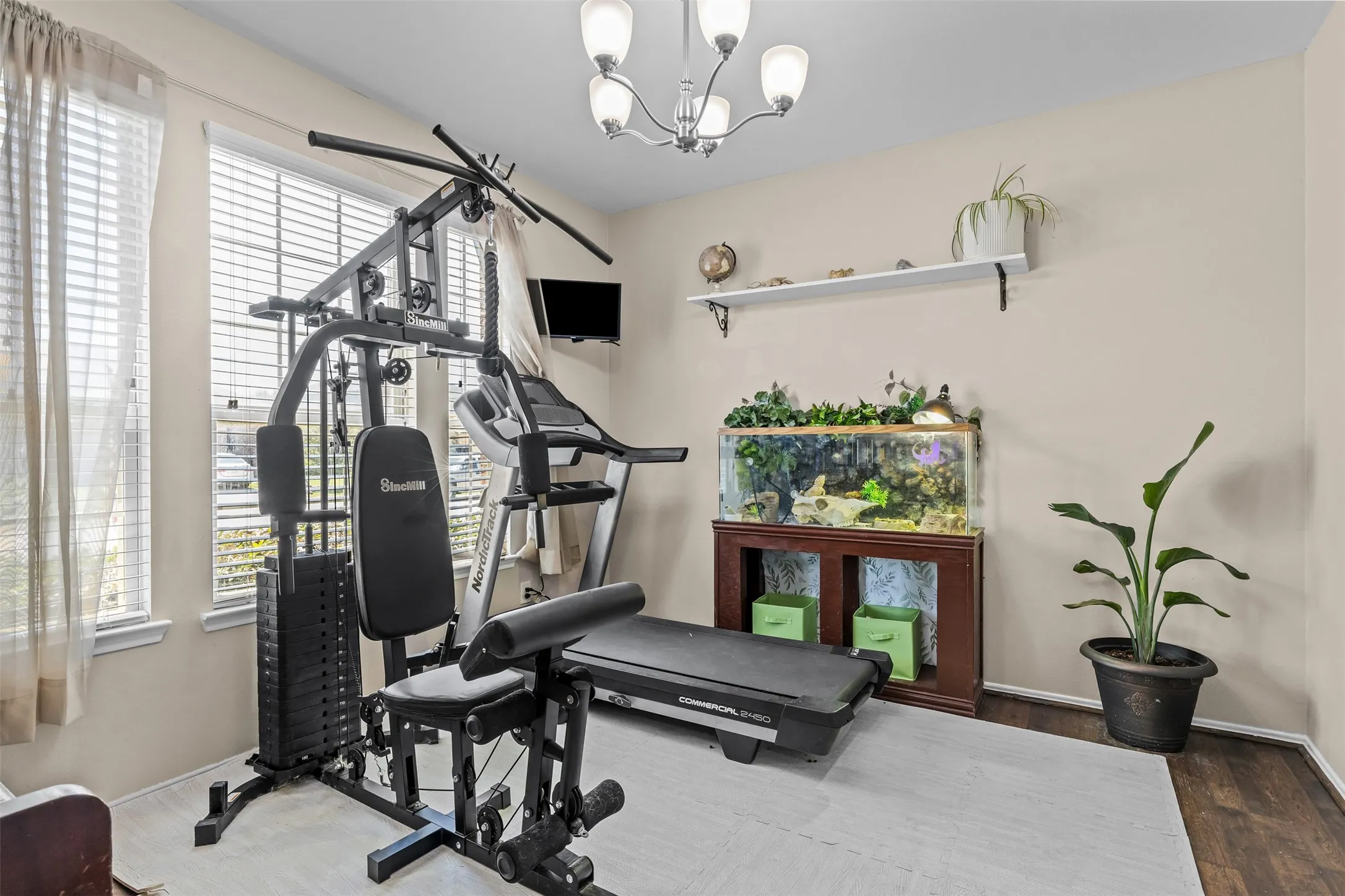 Home office just off entry with wood flooring, decorative lighting and large windows