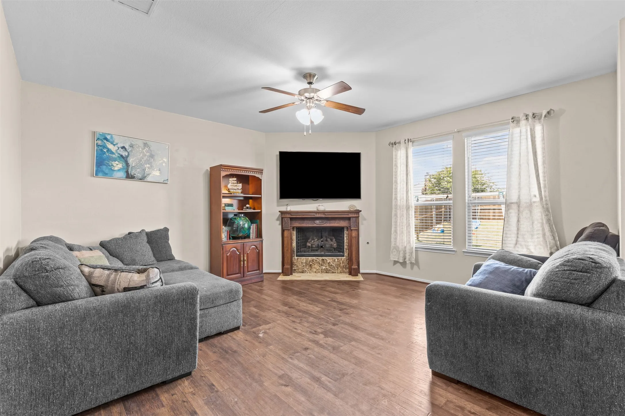 Open living area with beautiful wood flooring and a stone fireplace with mantle