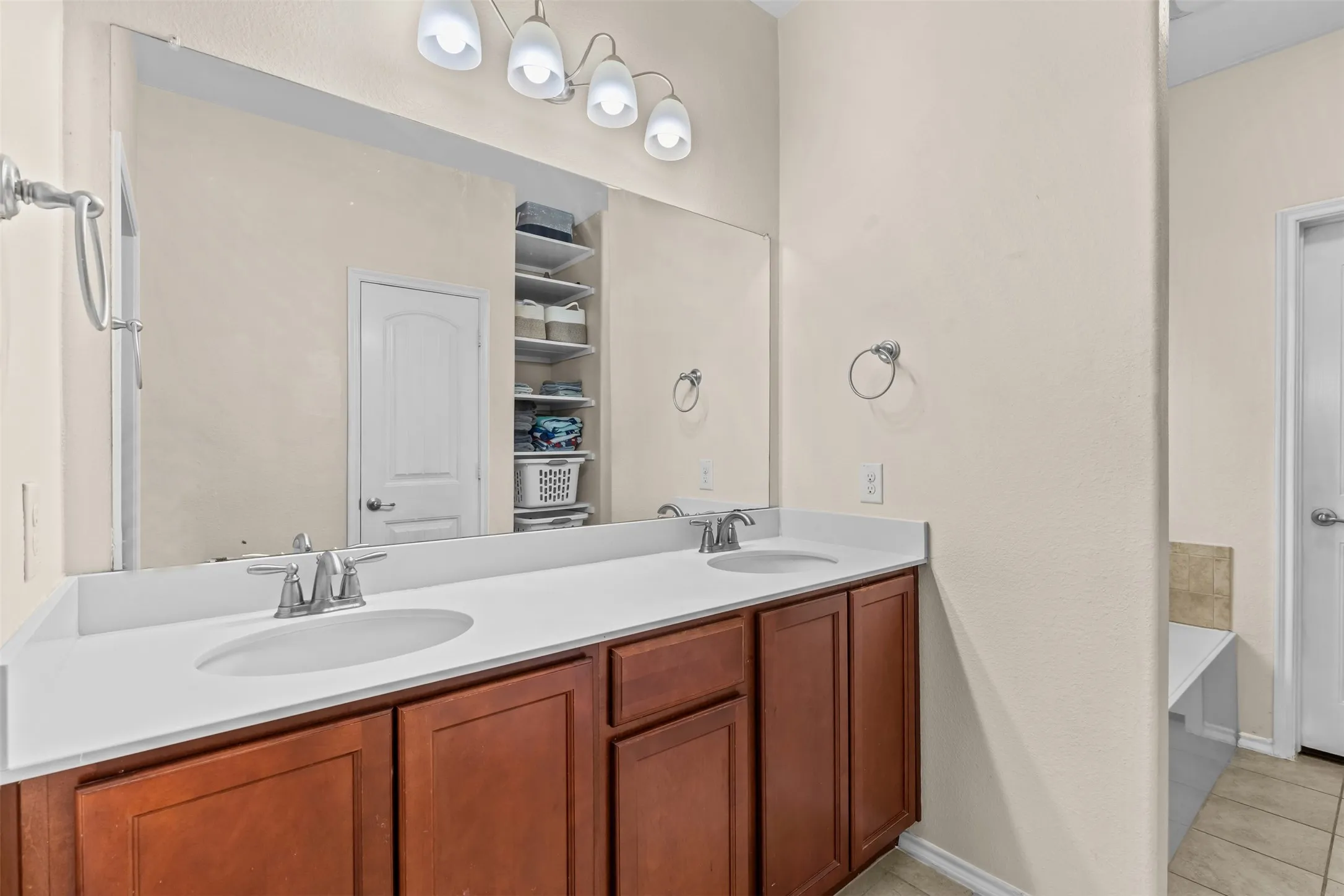 Bathroom features dual sinks and linen storage