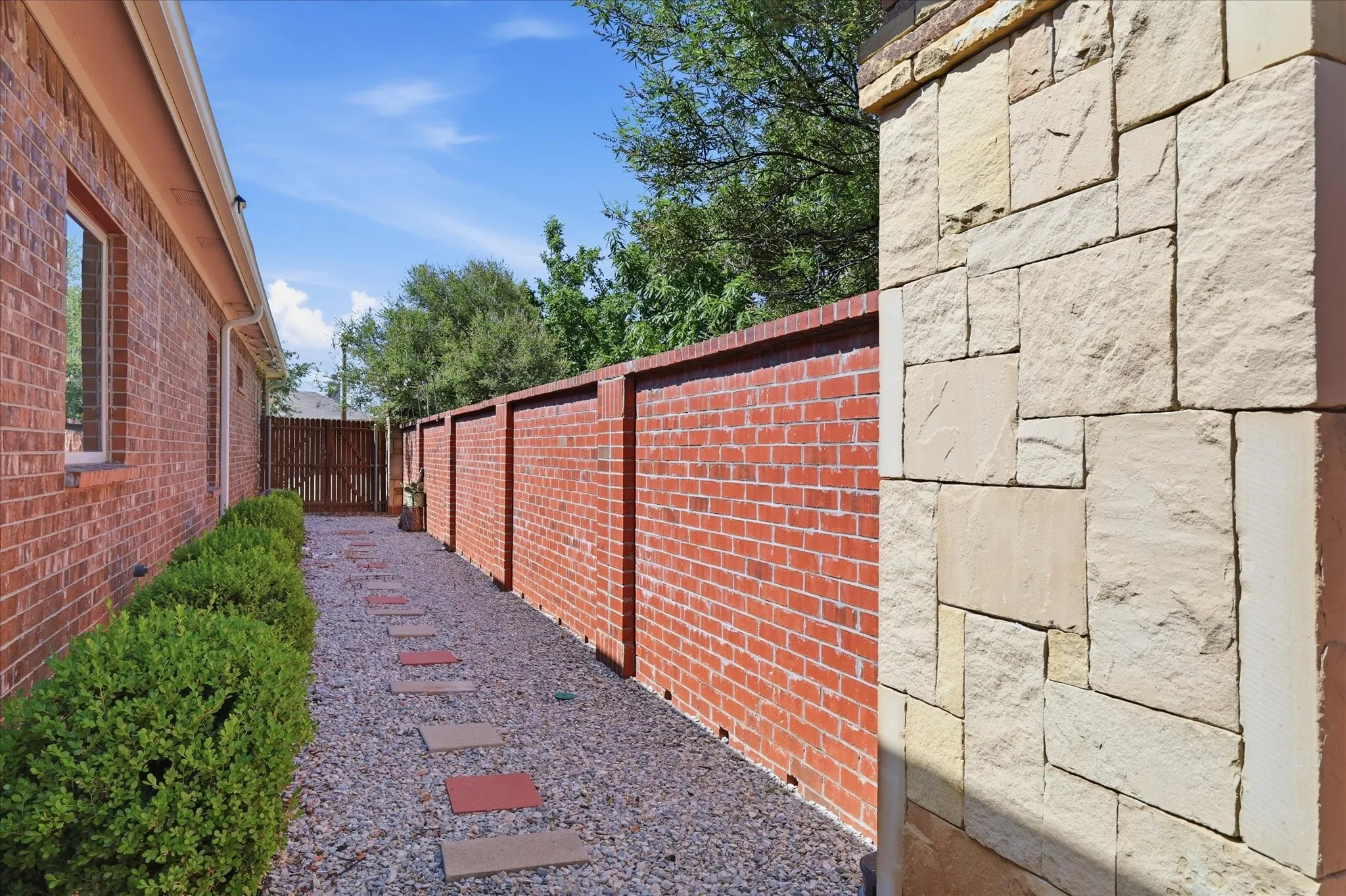 Side yard with gravel, custom pavers and brick fencing