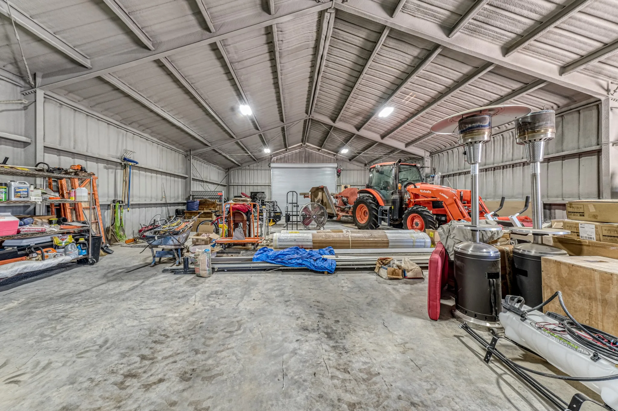 Spacious metal-sided outbuilding with a concrete floor, high vaulted ceiling, and overhead lighting