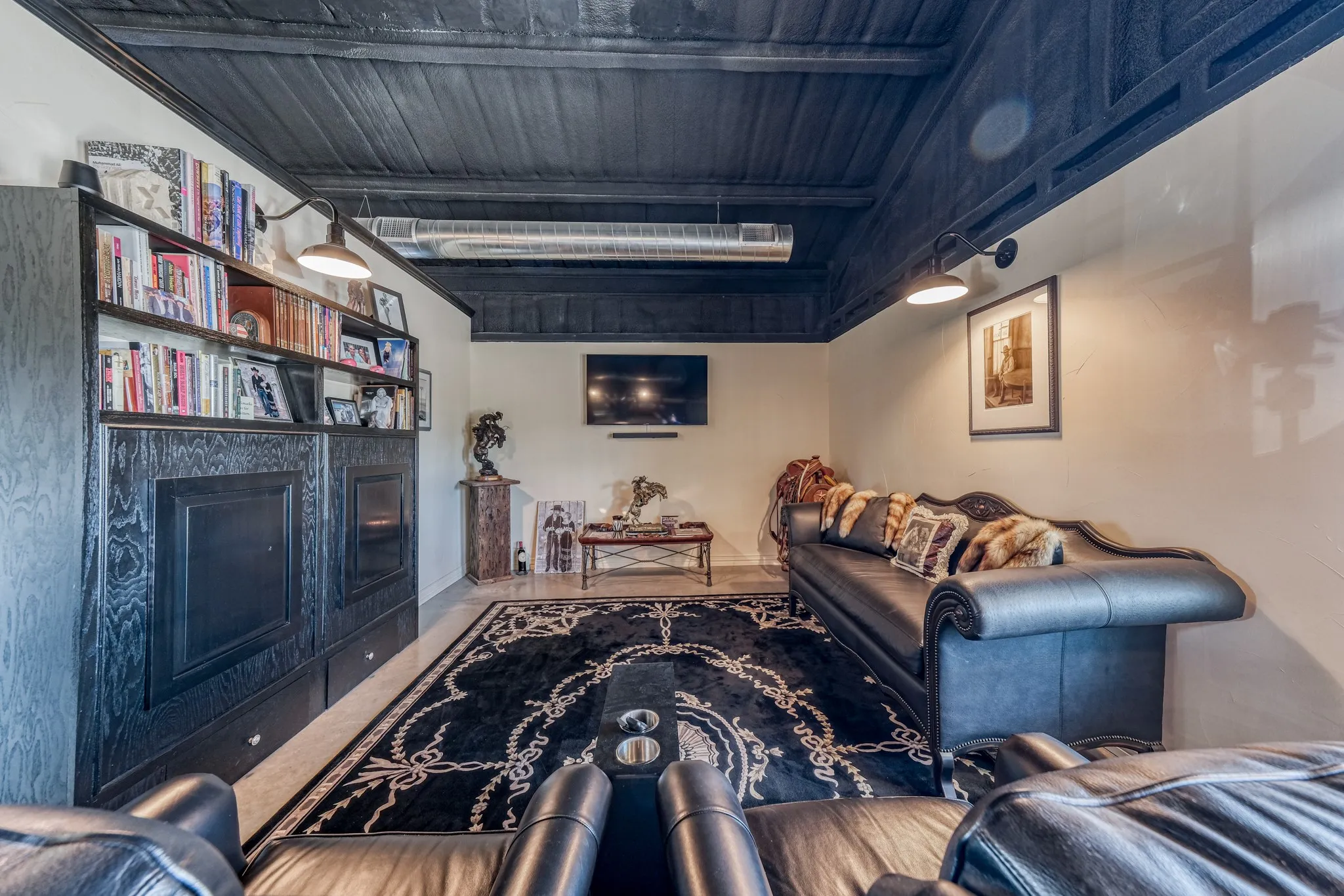 Living space featuring a dark wood-finish ceiling, built-in shelving, and wall-mounted sconce lighting