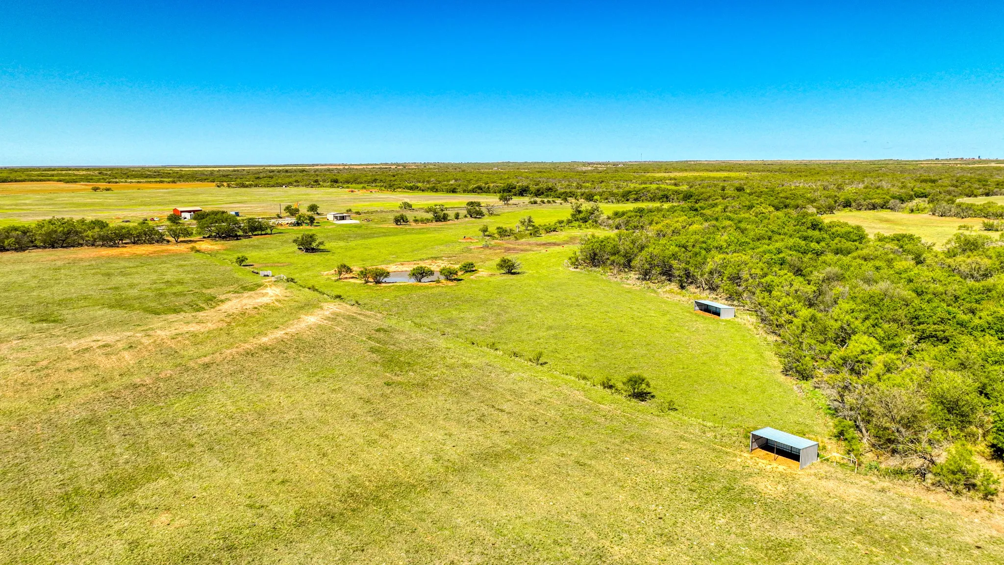 Expansive agricultural landscape featuring open fields and wooded areas