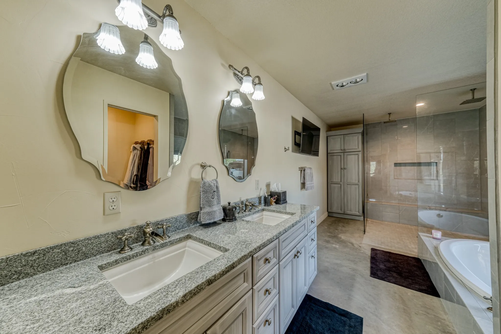 Double vanity with granite countertops, light-toned cabinetry, and decorative mirrors