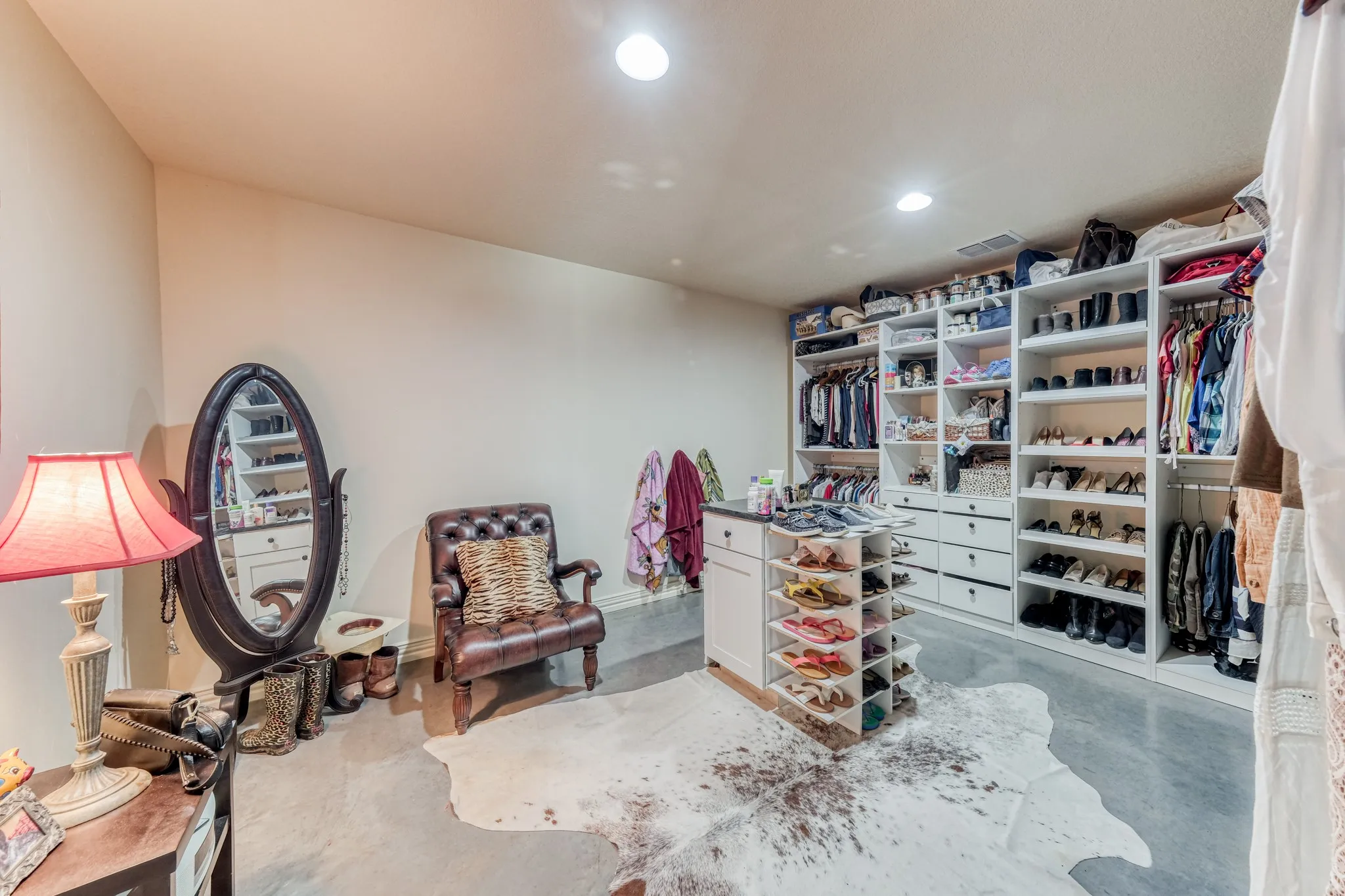 Spacious walk-in closet featuring extensive built-in shelving, multiple hanging rods, integrated drawers, and a central storage island with a dark countertop