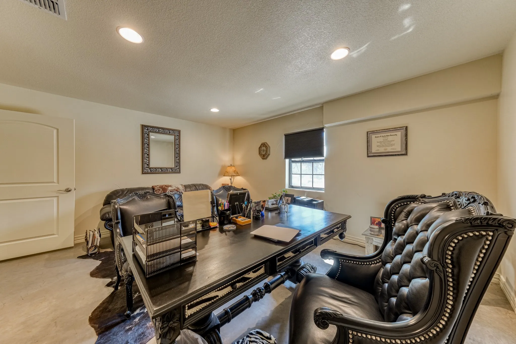 Spacious room featuring recessed lighting, a window with a blackout shade, a white paneled door, and light-toned walls