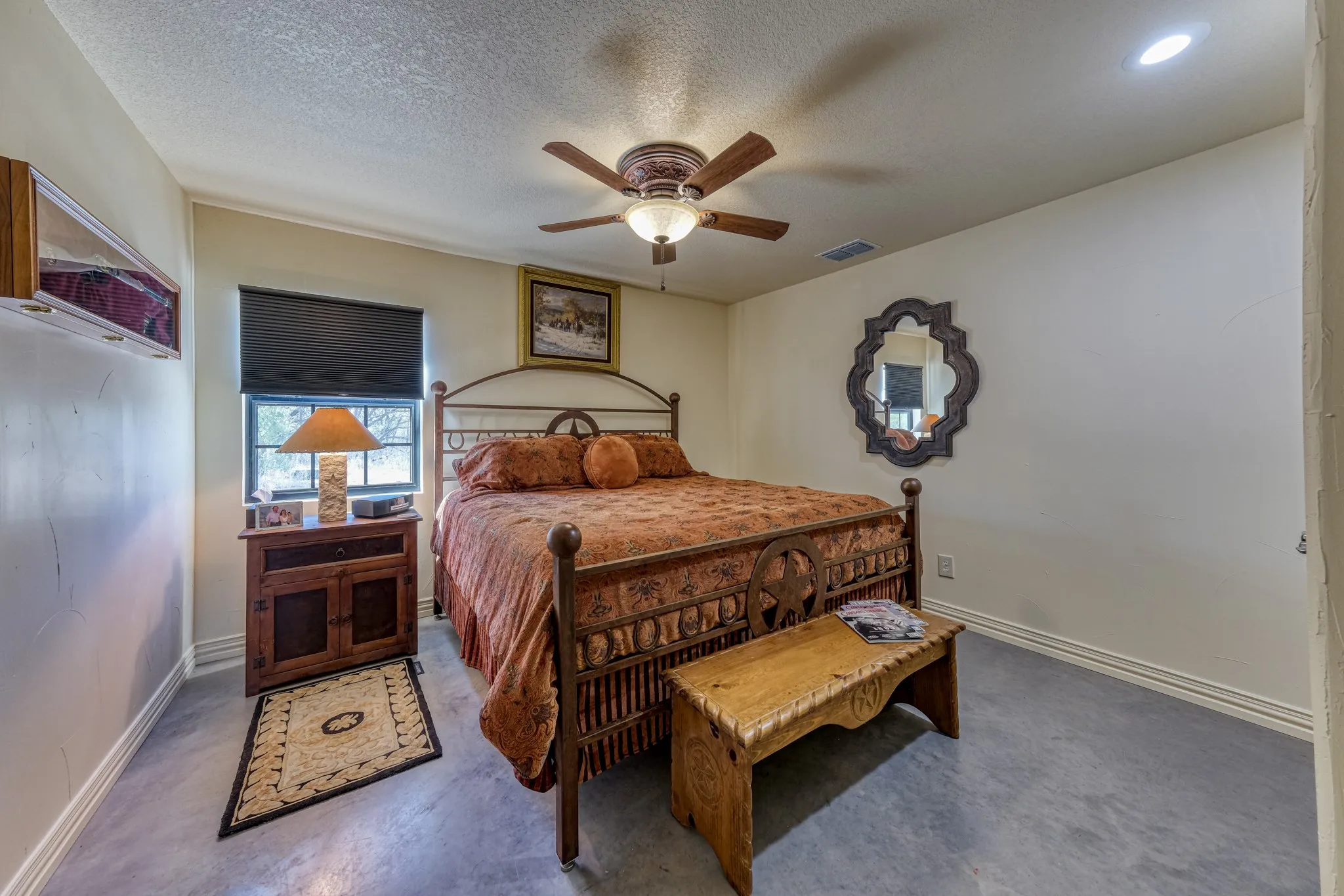 Bedroom featuring concrete flooring, a window with a dark blind, and a ceiling fan with integrated lighting