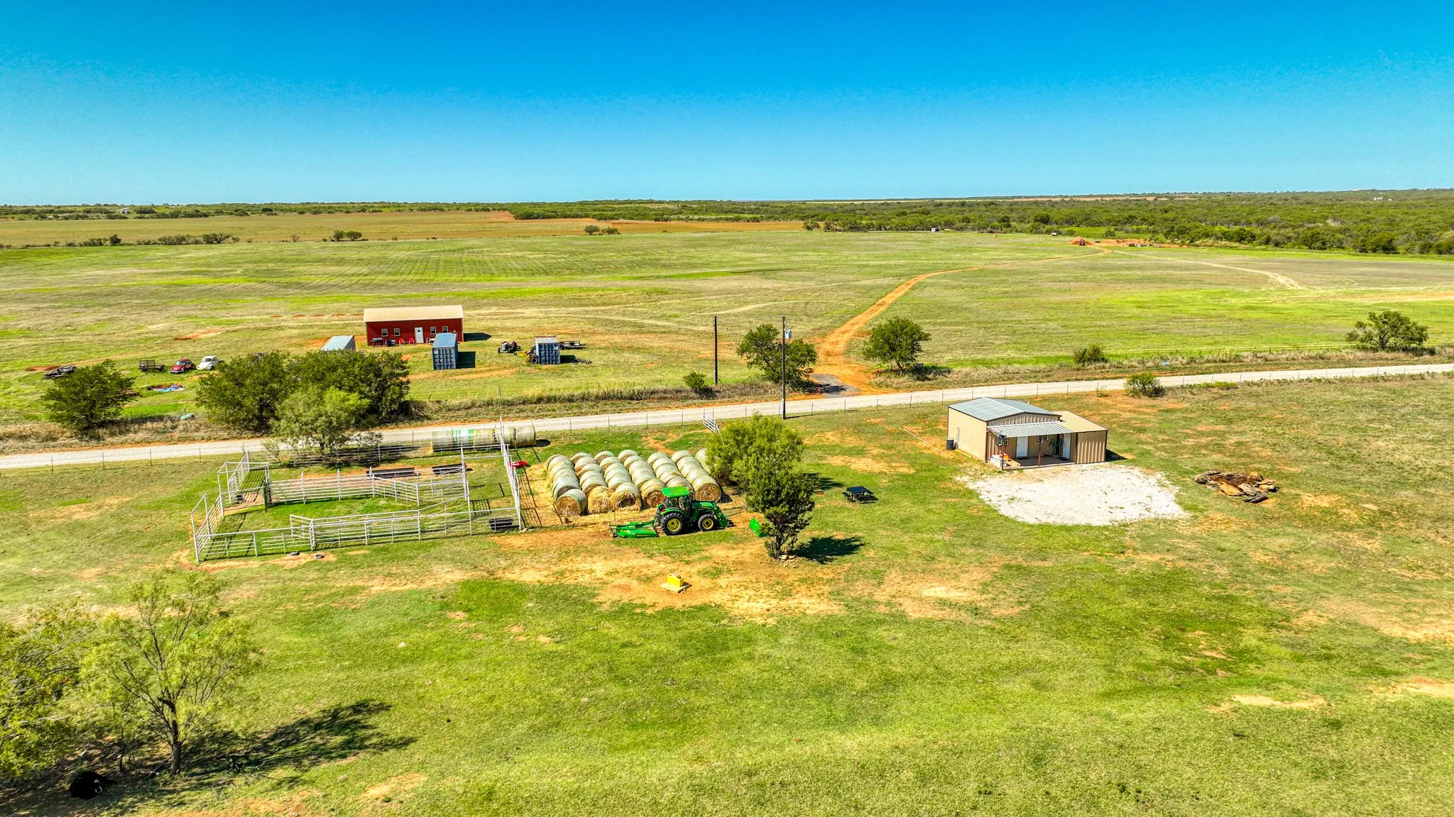 Expansive rural property featuring a red barn, a metal outbuilding, and a fenced enclosure