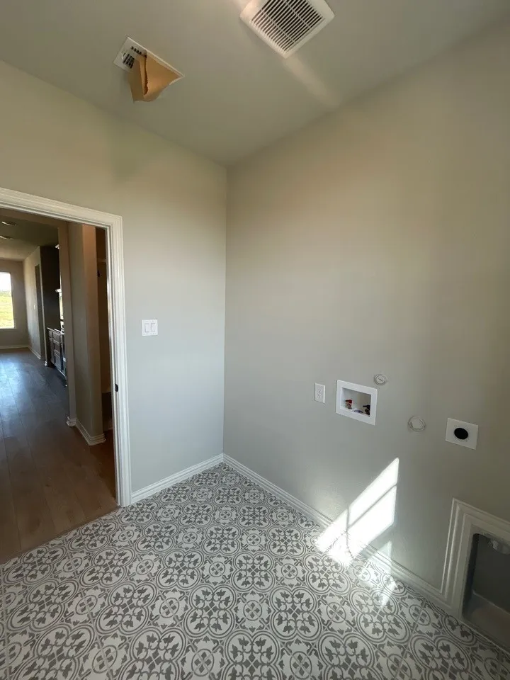 Decorative tile flooring, light-toned walls, and laundry hookups