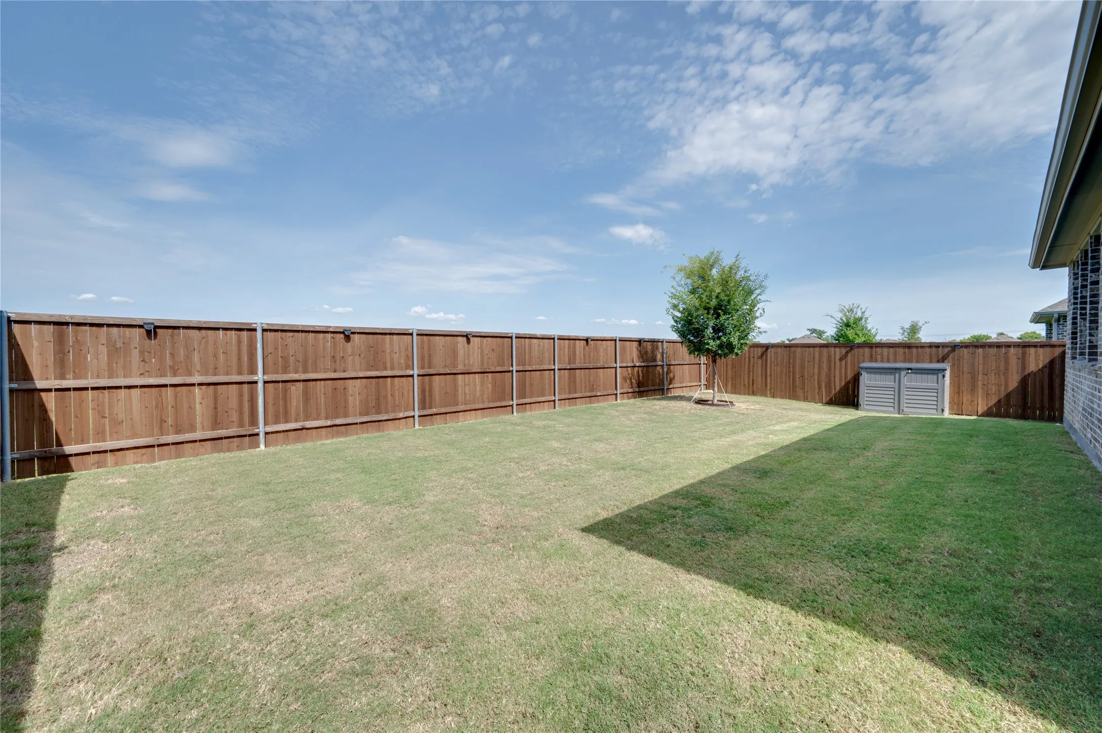 Large backyard with shed including lawn equipment.