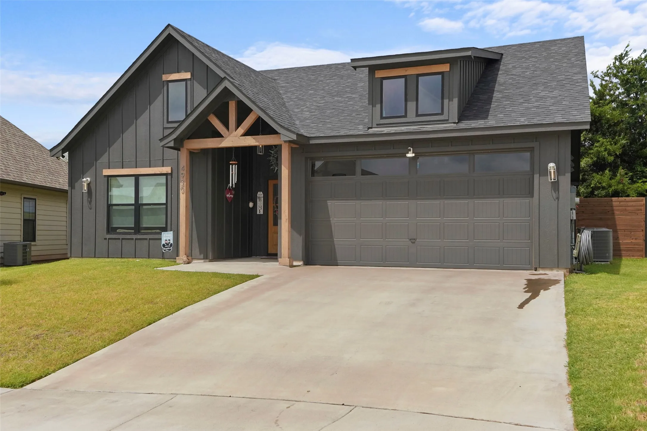 Contemporary exterior with dark vertical siding, wood-toned architectural accents, and a two-car garage