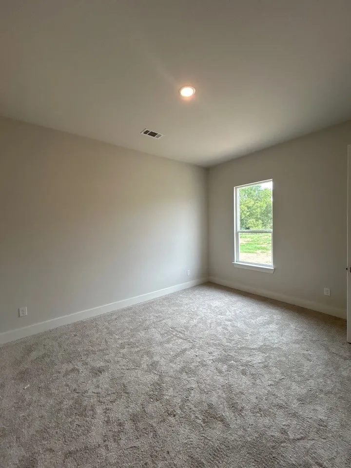 Neutral tone wall paint, recessed ceiling lighting, light-toned carpeting, and a window with white trim