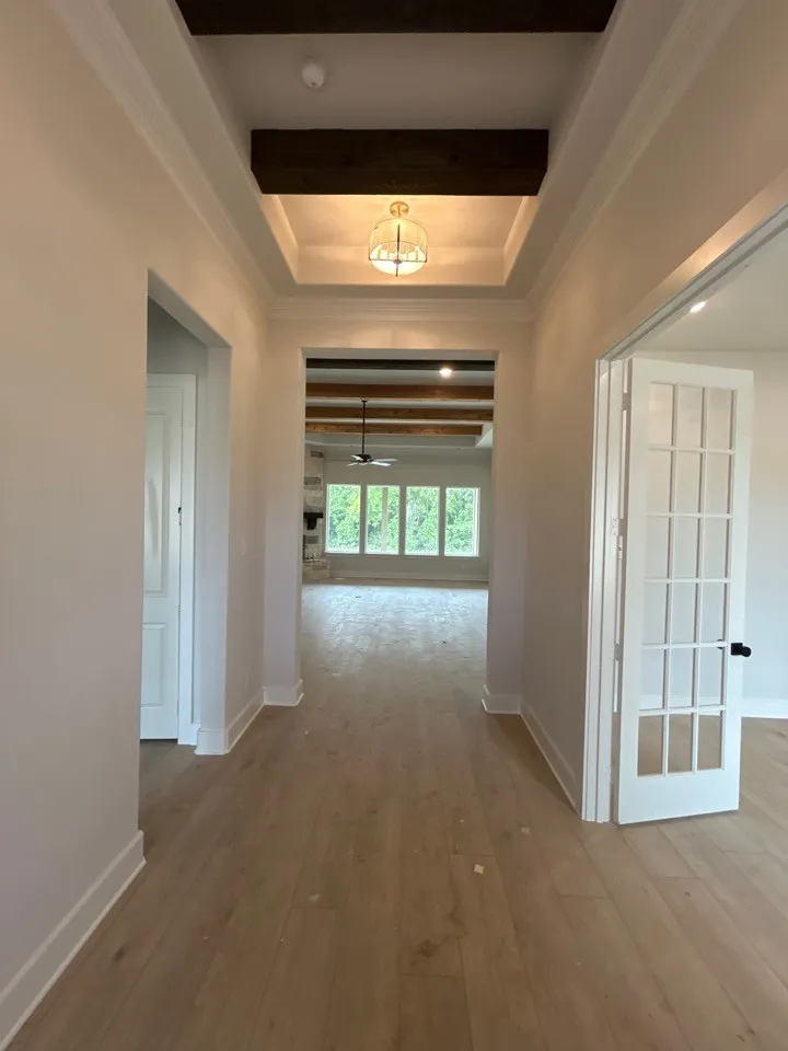Foyer featuring wood-finish flooring, a tray ceiling with a decorative light fixture, and crown molding