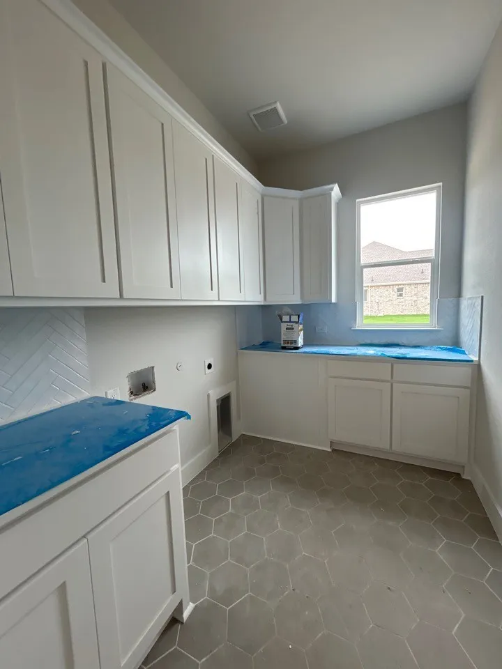 White shaker cabinetry with crown molding, hexagon tile flooring, and a window for natural light