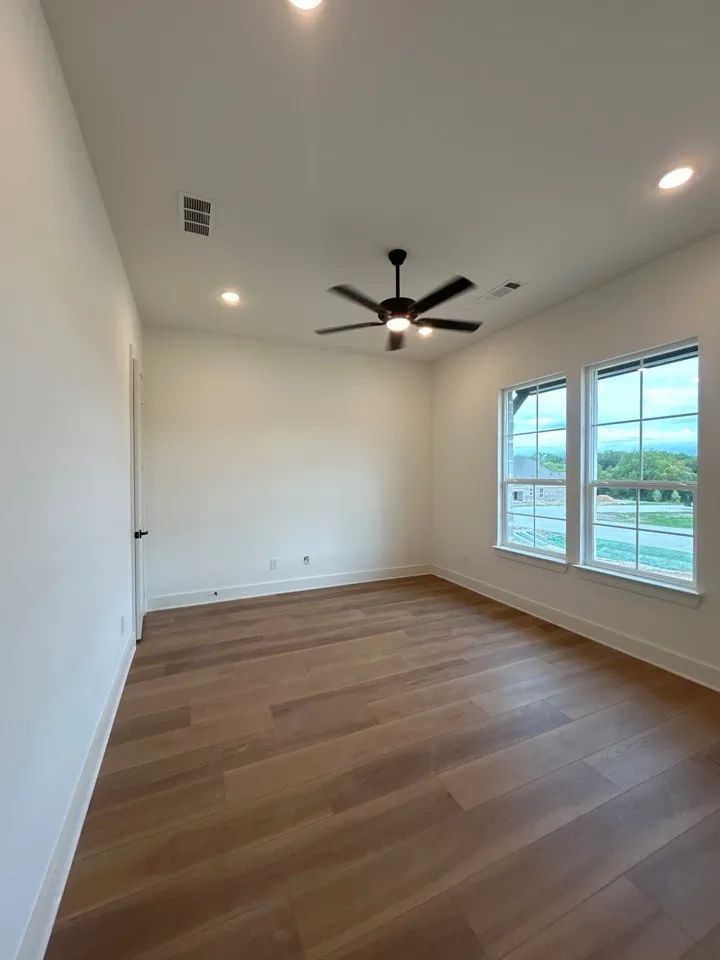 Neutral wall color, wood-finish flooring, recessed lighting, ceiling fan, and multiple windows