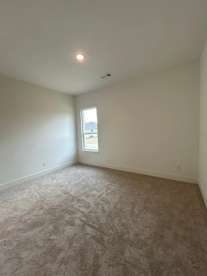 Soft-pile carpet flooring, recessed ceiling lighting, and a single window with white trim