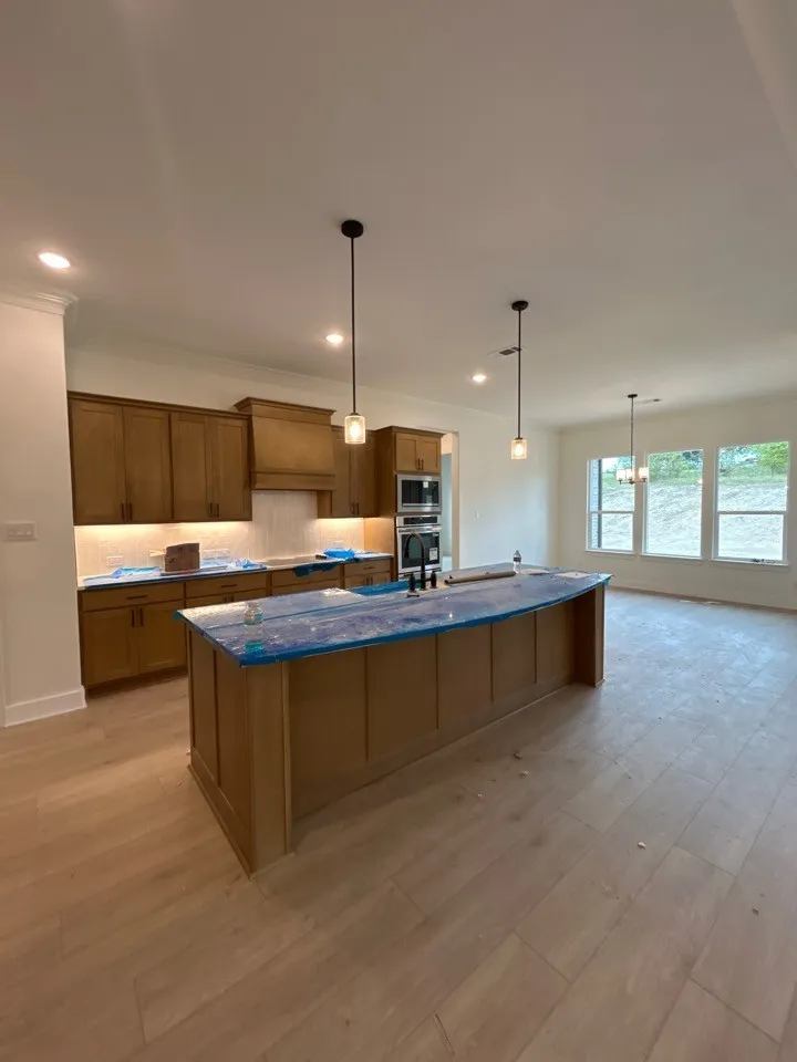 Wood-finish flooring throughout, with a kitchen island featuring integrated sink and pendant lighting