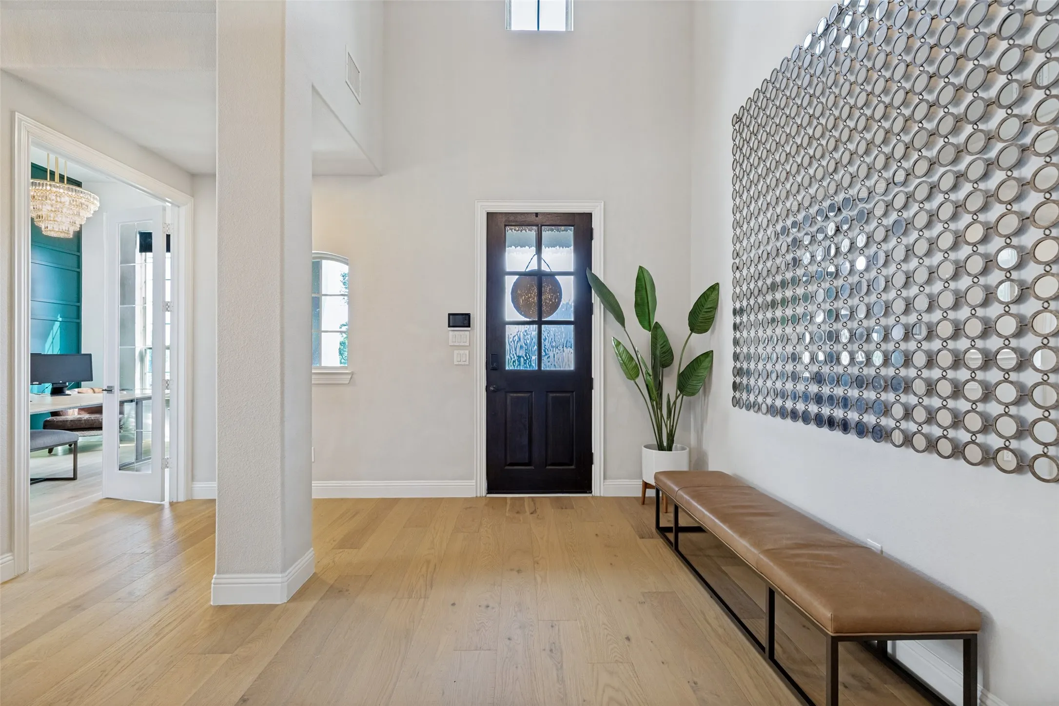 Entryway featuring light wood-finish flooring, a dark wood-paneled door with glass inserts, and a high vaulted ceiling