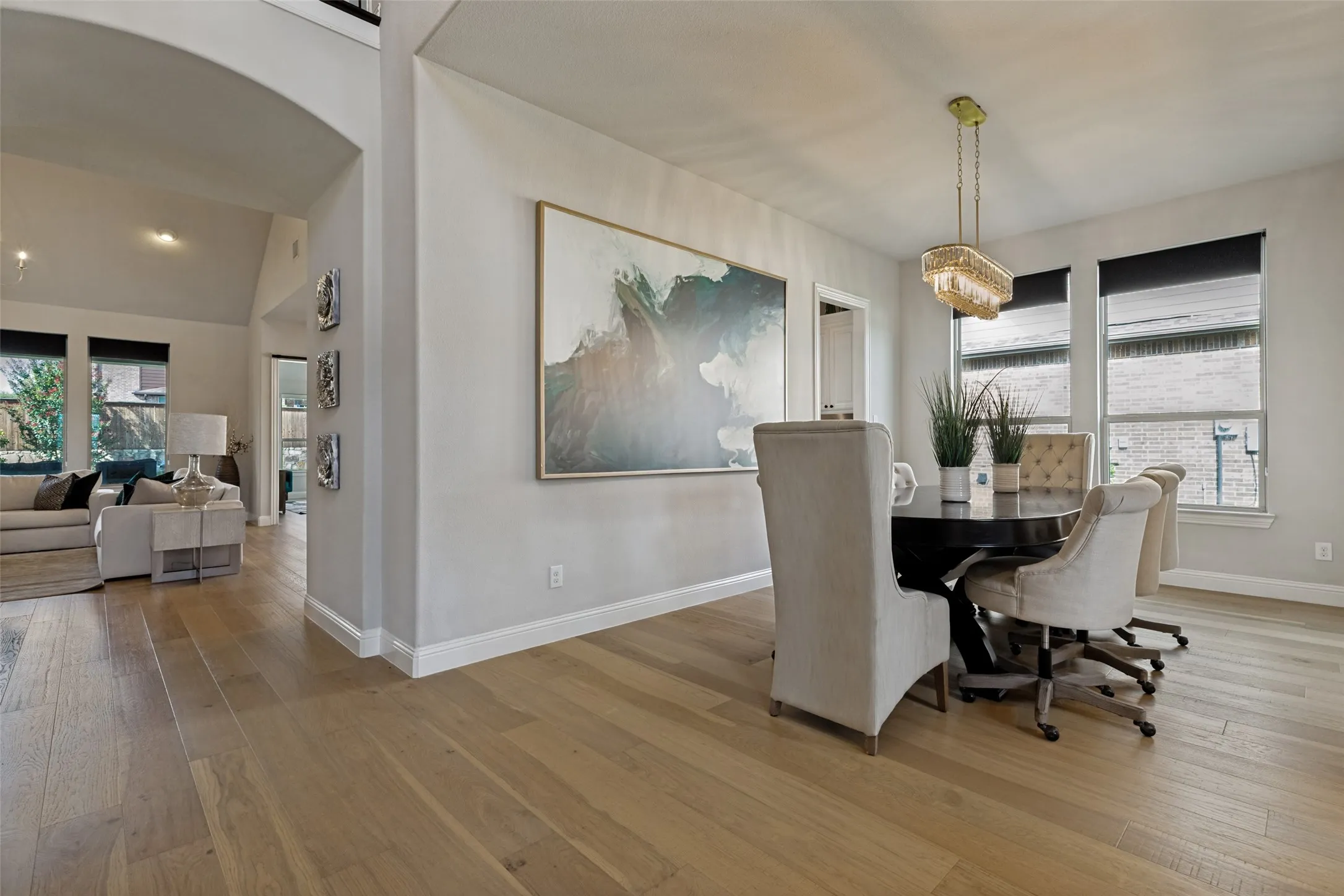 Spacious dining area featuring wood-finish flooring, a contemporary chandelier, multiple windows, and wide baseboards