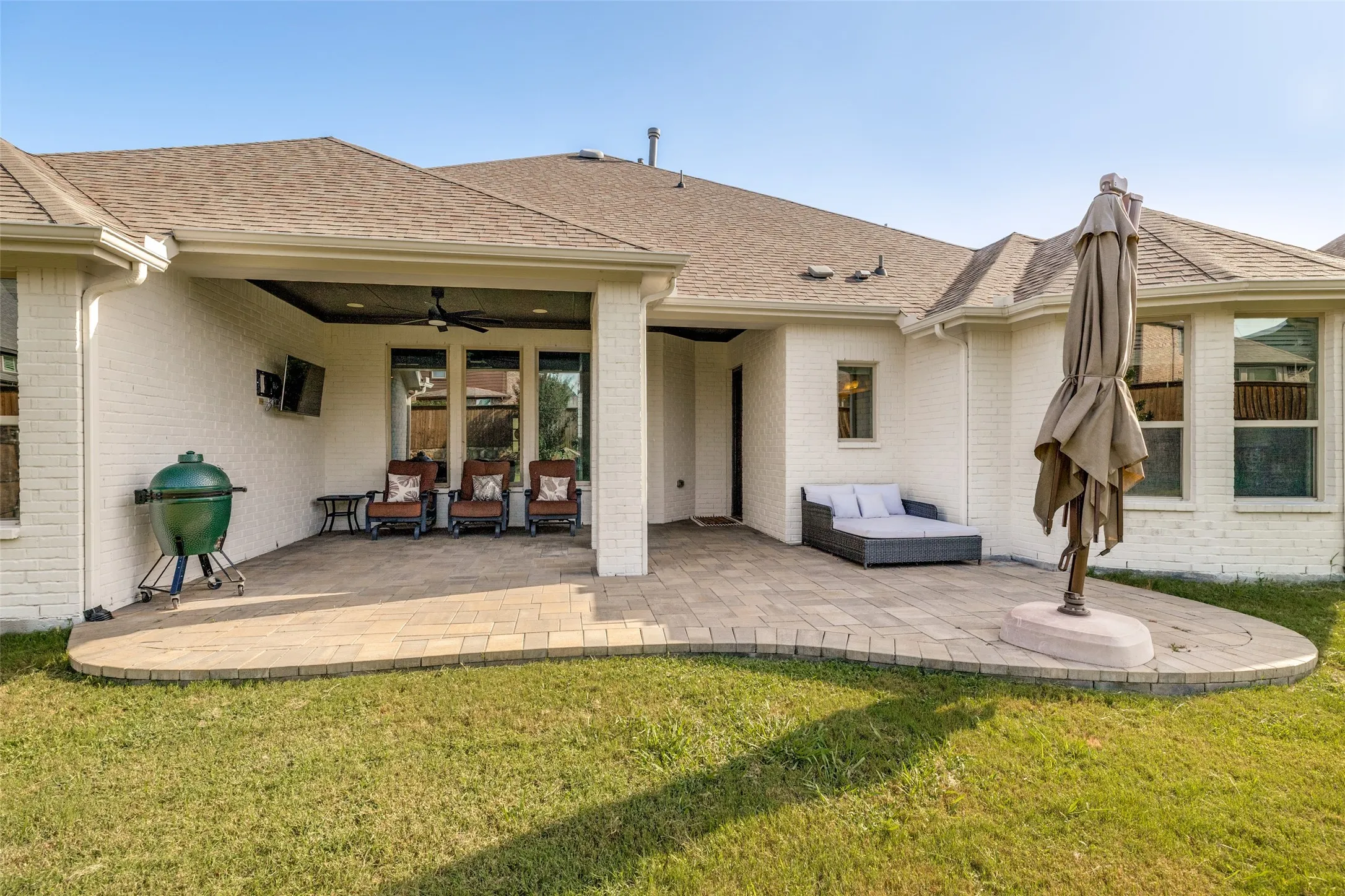 Expansive paver patio featuring a covered outdoor living area with a ceiling fan