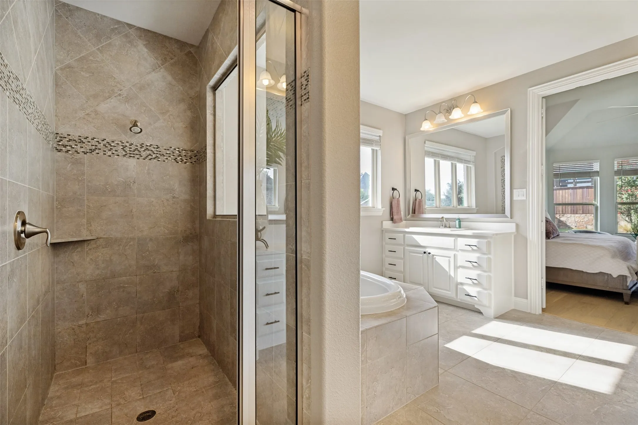 Glass-enclosed shower with tile surround and decorative accent band