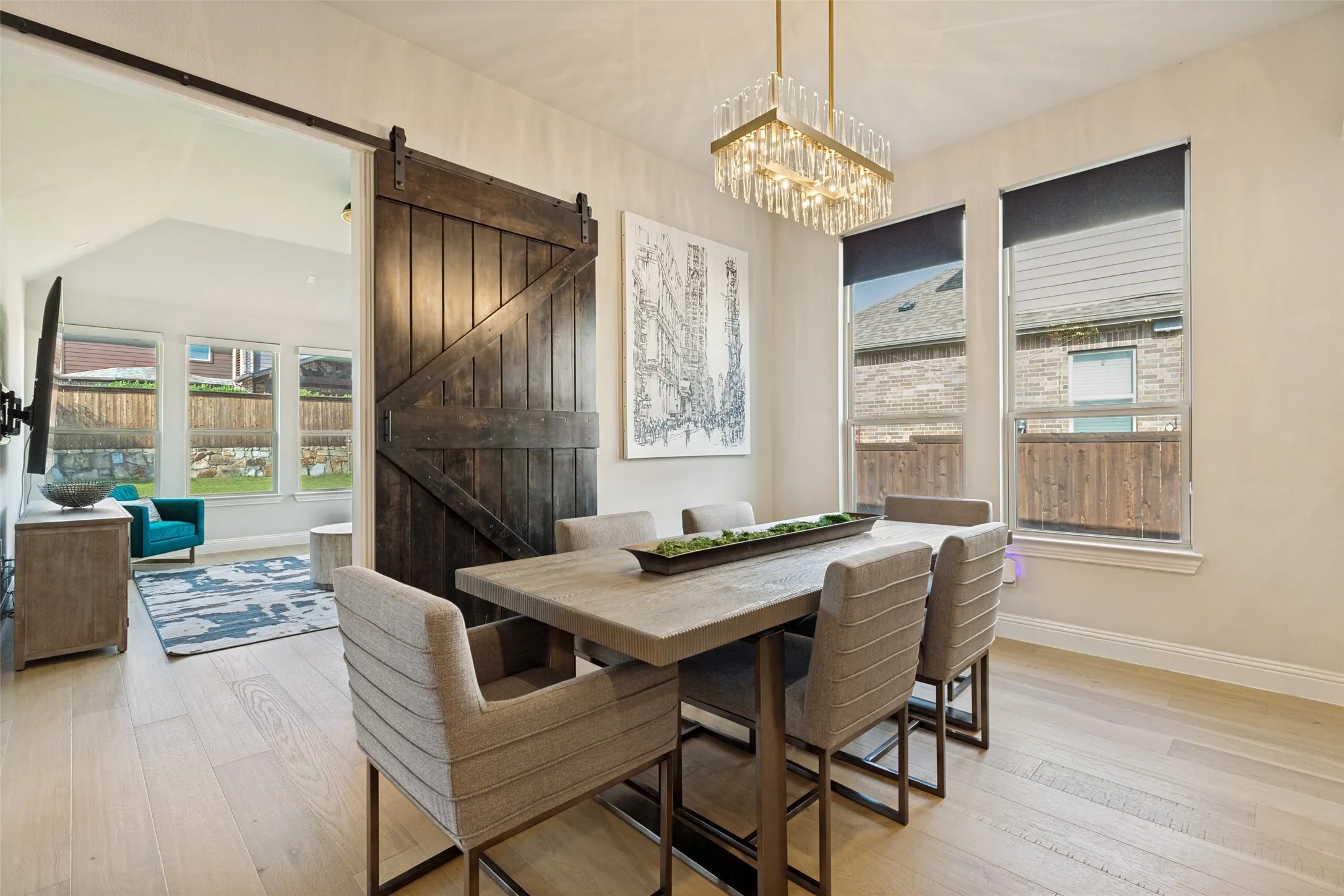 Dining area featuring wood-finish flooring, a rectangular chandelier with crystal accents, and multiple windows
