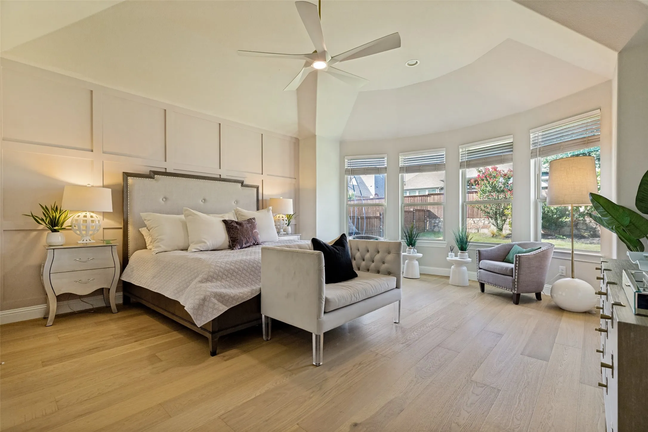 Spacious room featuring wood-finish flooring, a tray ceiling, and a ceiling fan