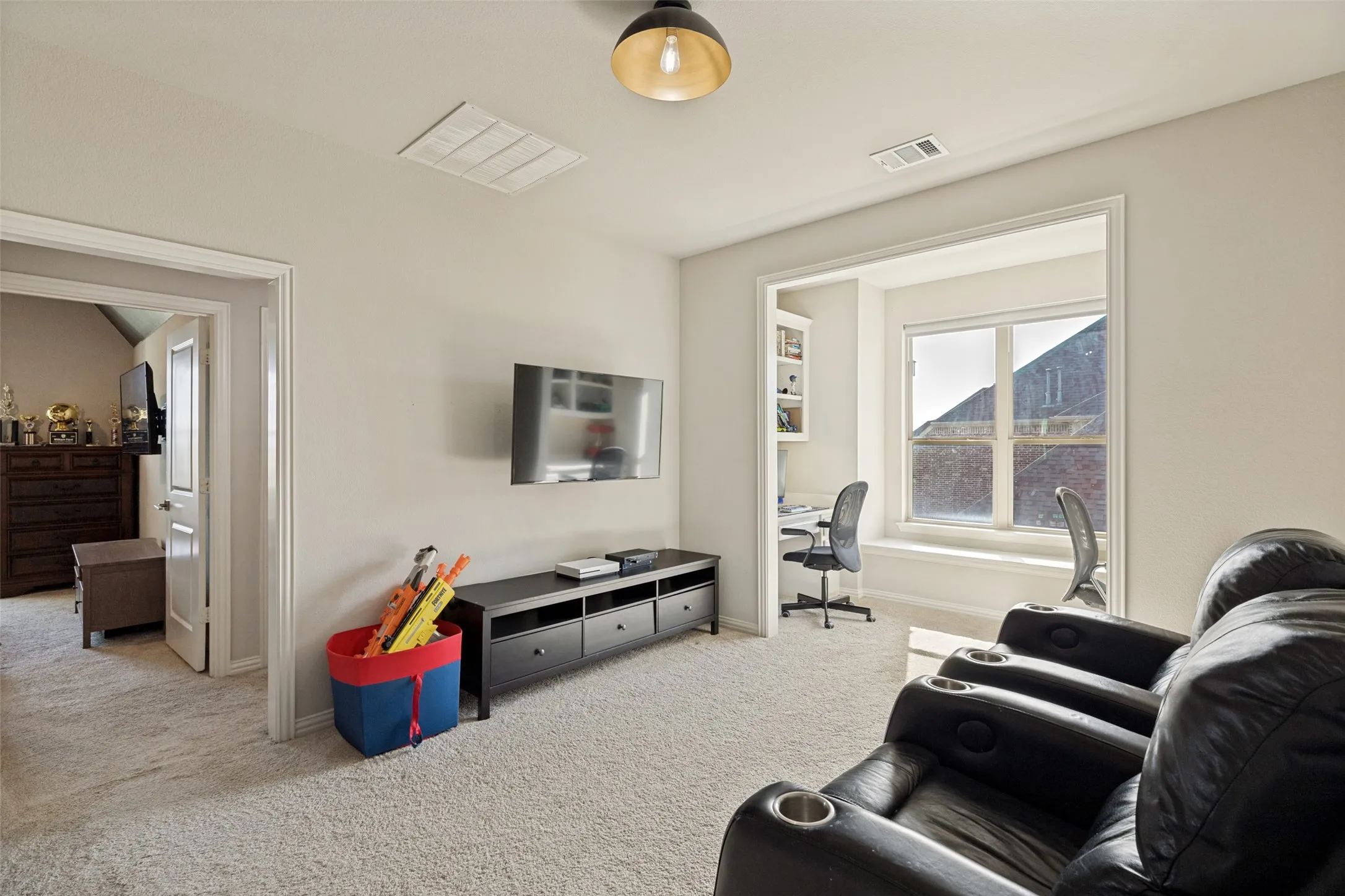 Carpeted room featuring a built-in window seat, recessed study nook with built-in shelving, and a mounted ceiling light fixture
