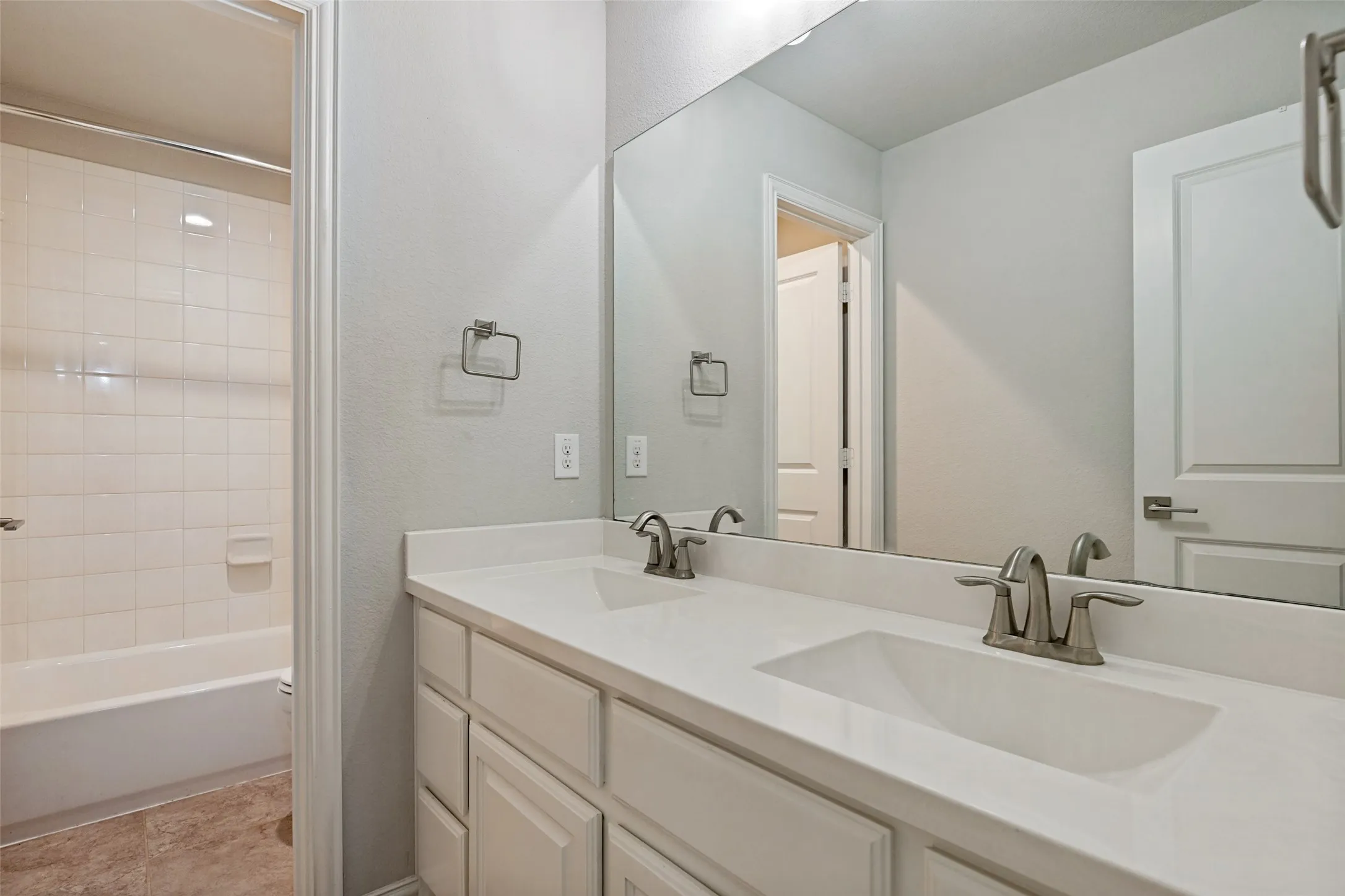 Bathroom featuring a dual vanity with white cabinetry, integrated sinks, and brushed nickel fixtures