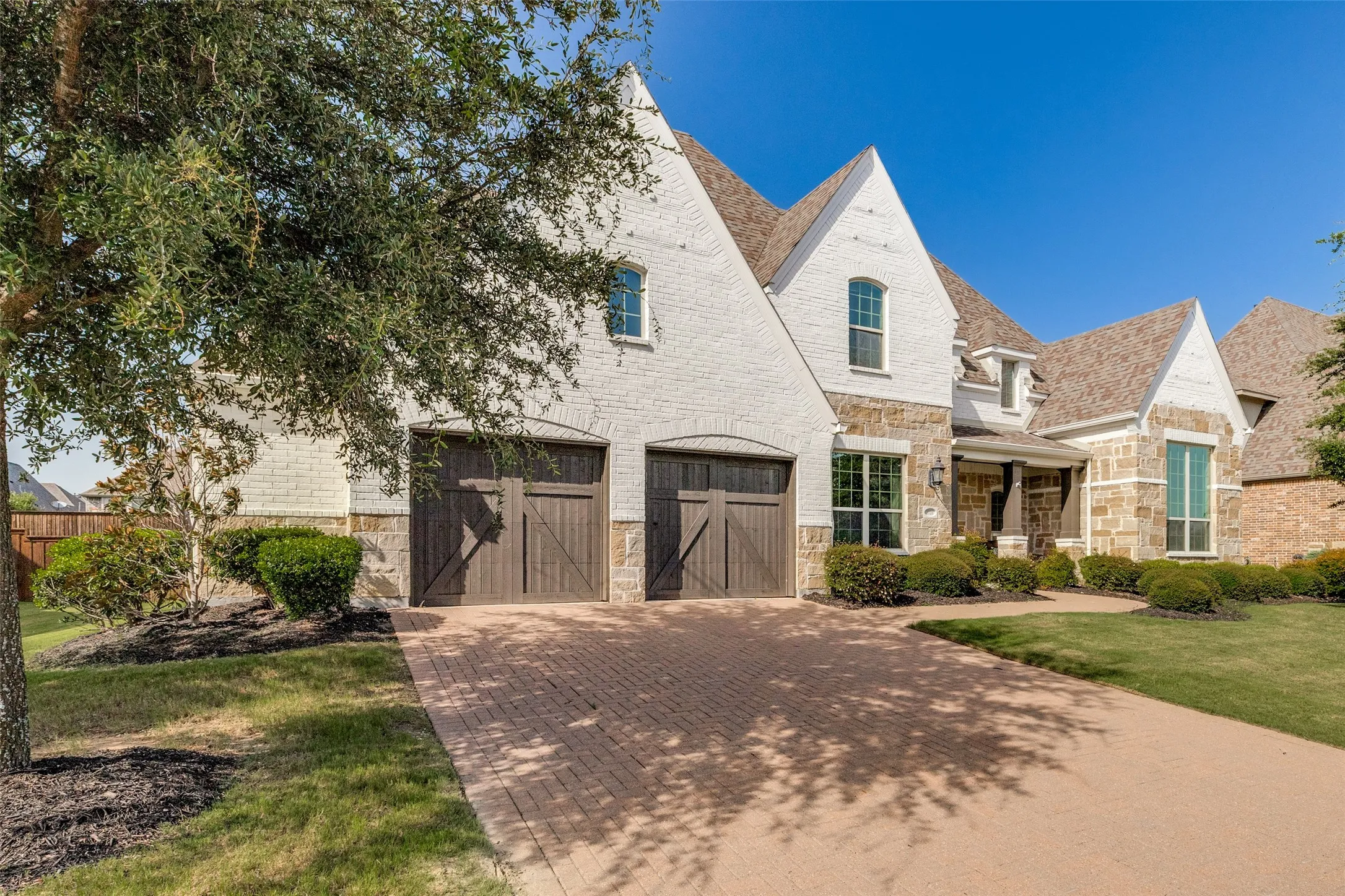 Two-story residence featuring a white brick and stone facade with multiple gables