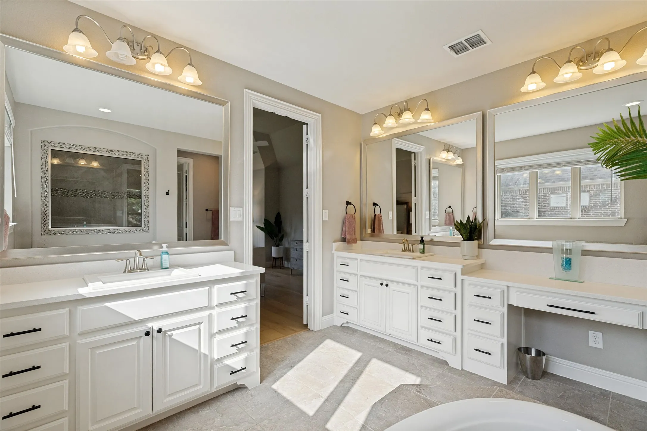 Spacious bathroom featuring dual vanities with white cabinetry, ample storage, and undermount sinks