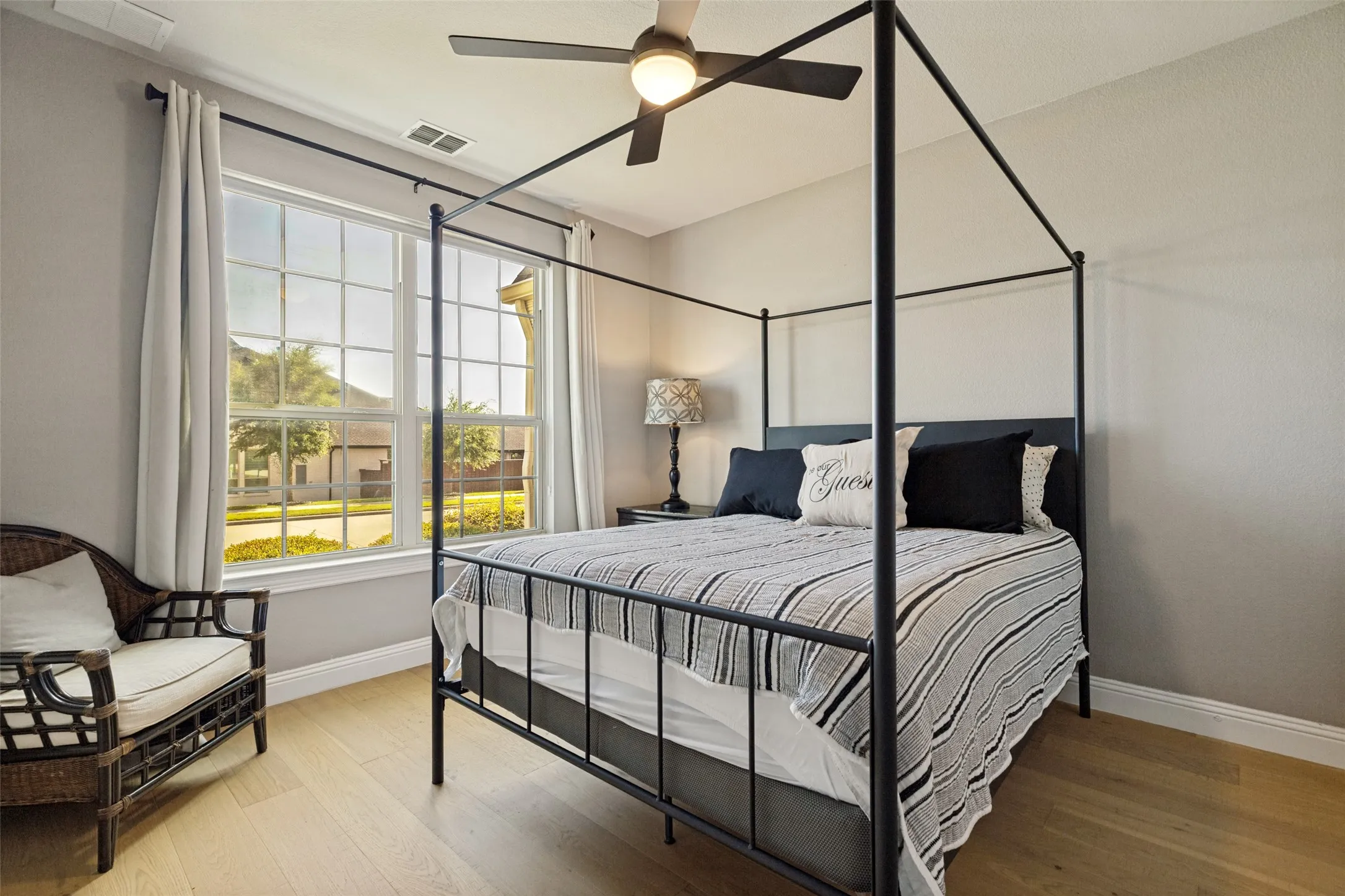 Room featuring a large multi-pane window with white trim, light wood-finish flooring, a ceiling fan, and light-toned wall paint