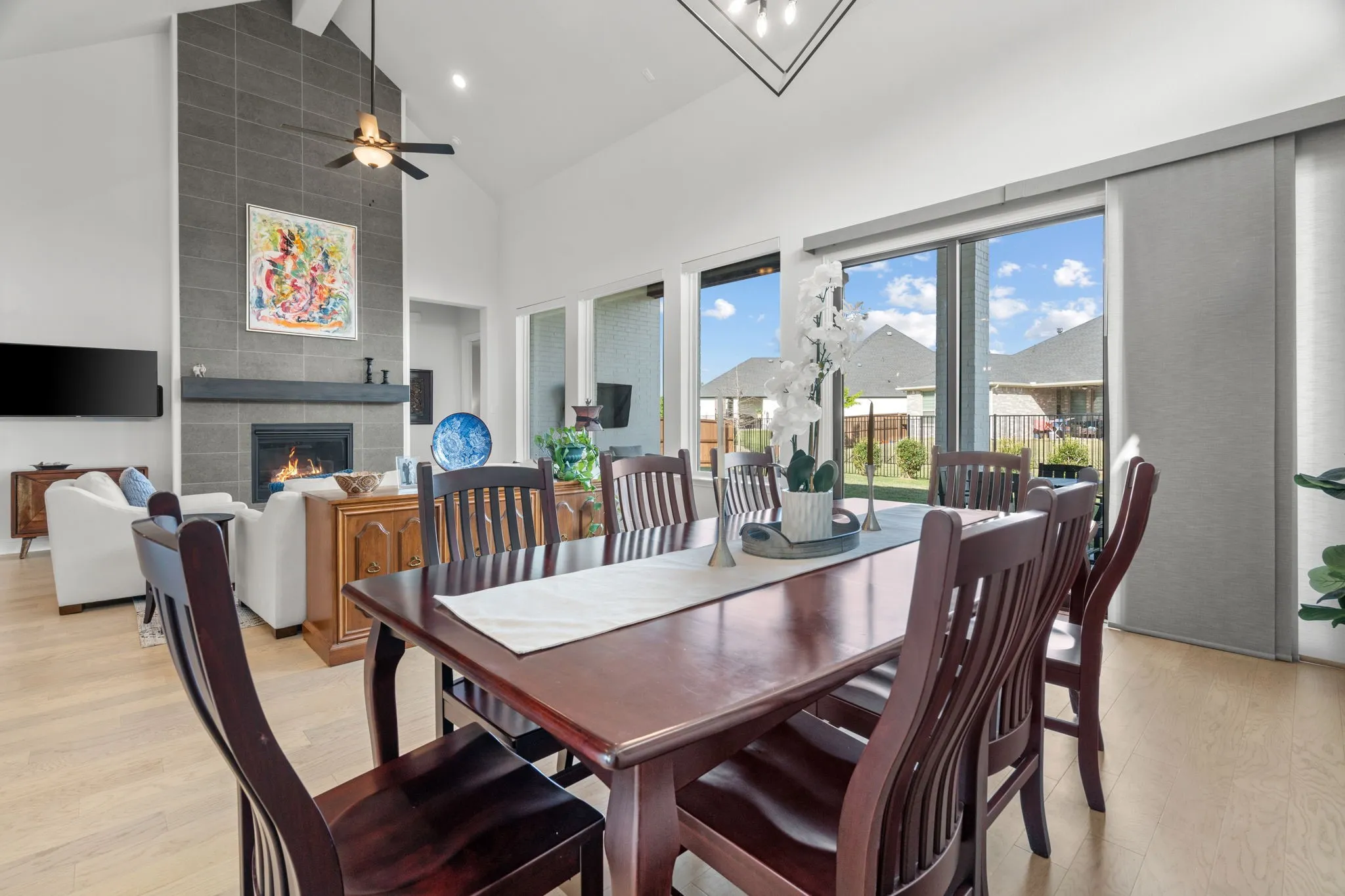 Open-concept living space with a vaulted ceiling, wood-finish flooring, and a fireplace featuring a floor-to-ceiling tile surround