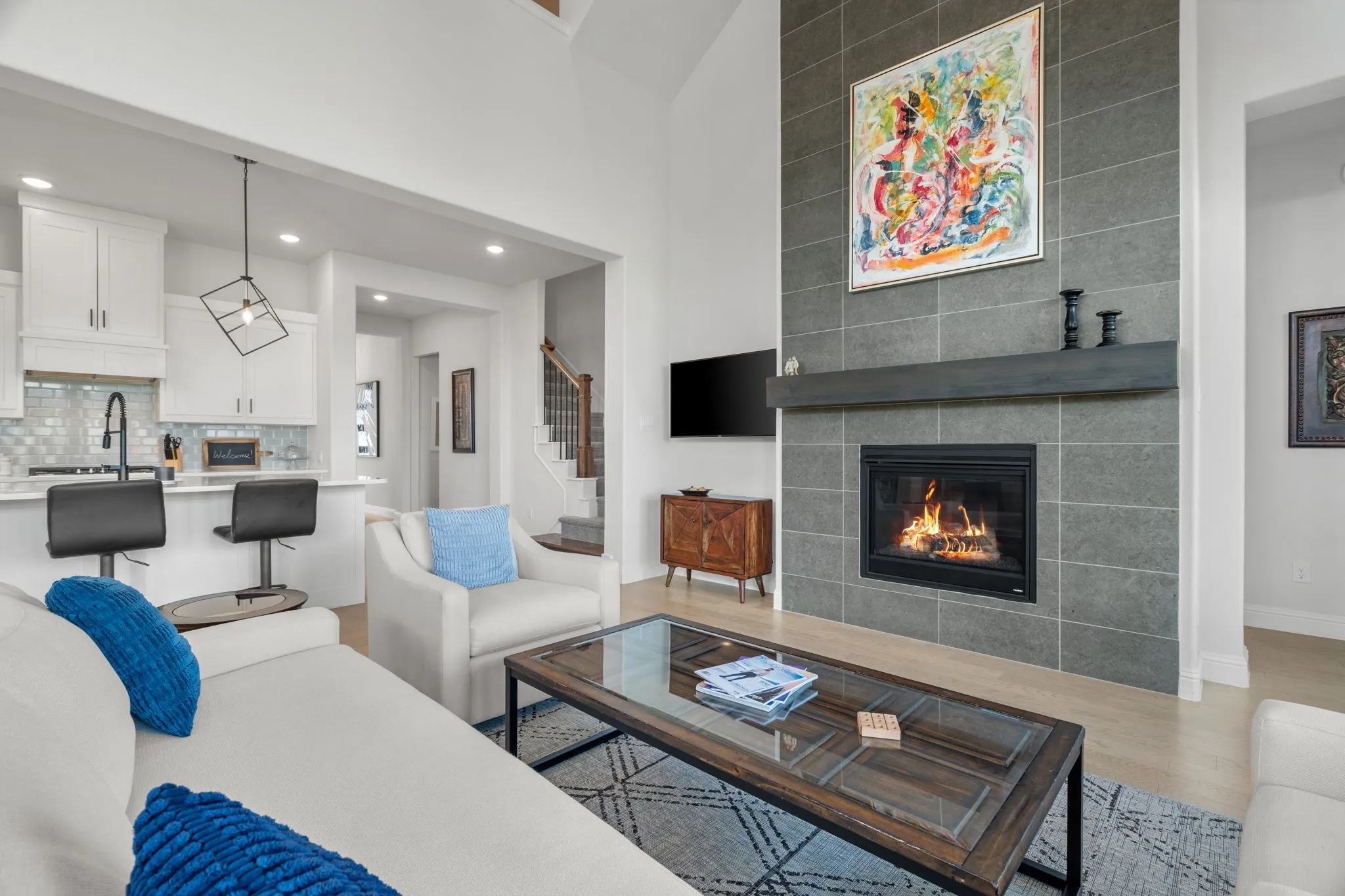 Vaulted ceiling living area featuring a floor-to-ceiling tiled fireplace with a dark wood mantel, recessed lighting, and light wood-finish flooring